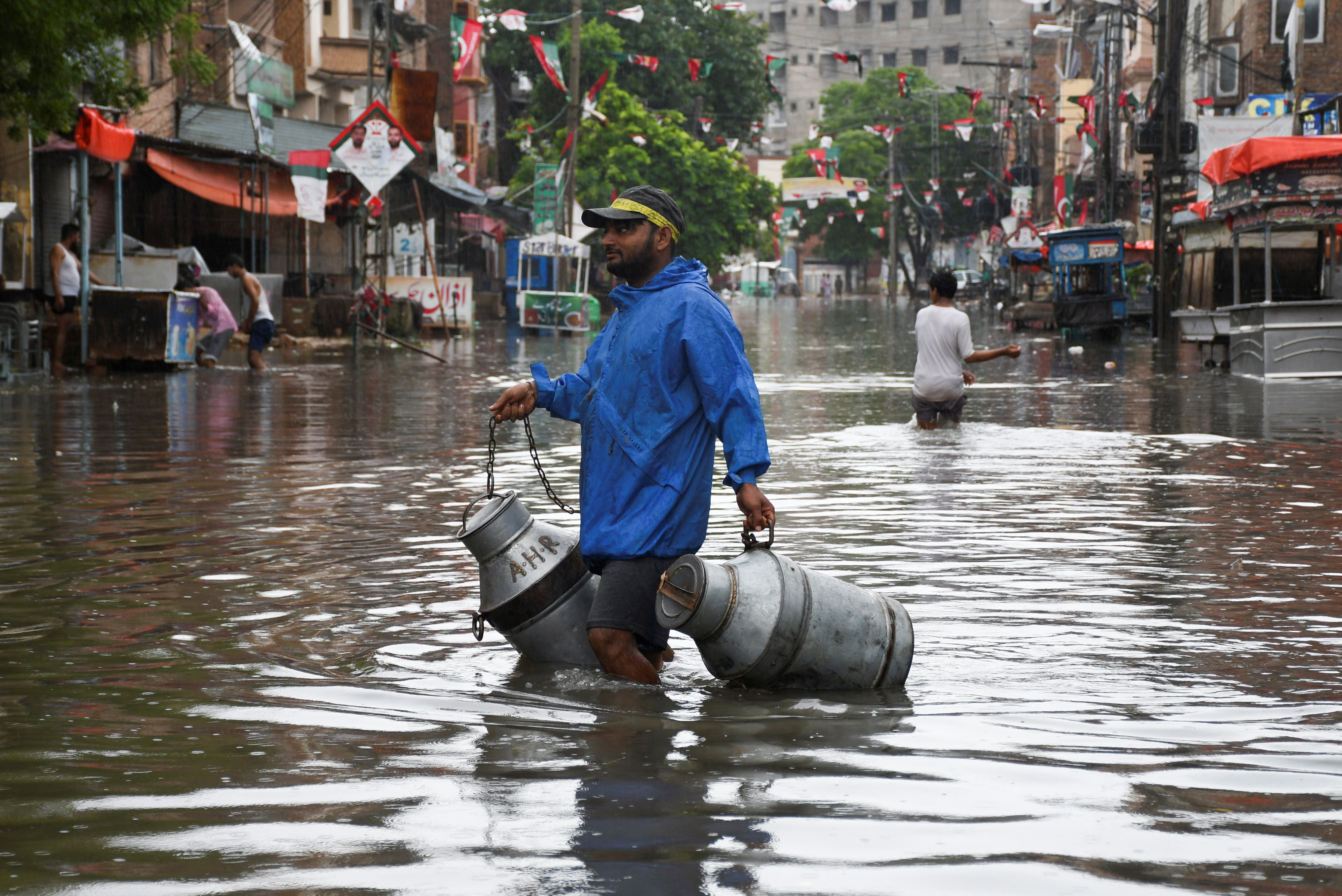 A man with milk-canisters walks along a flooded street, following rains during the monsoon season in Hyderabad