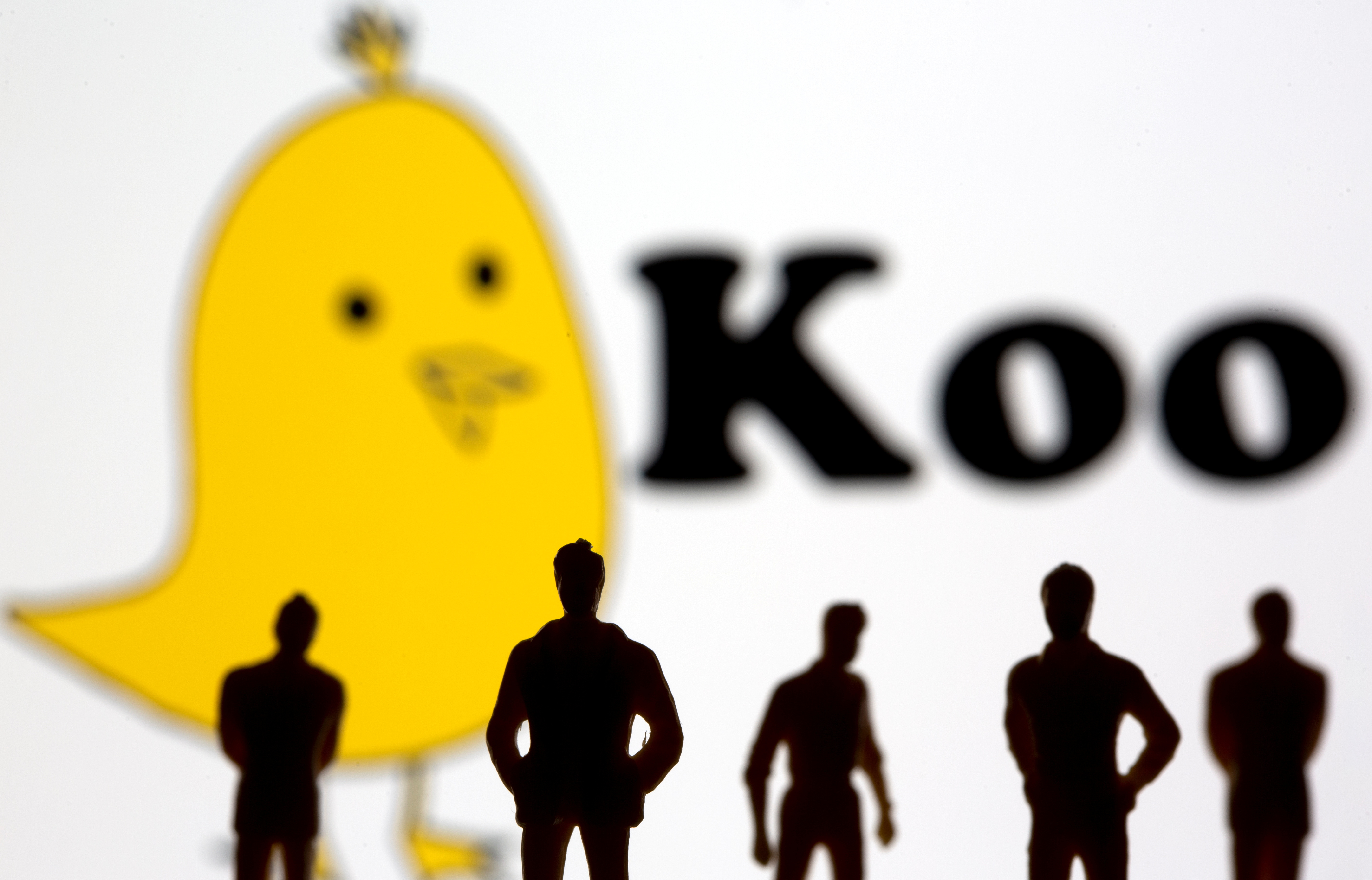 Small toy figures are seen in front of displayed Koo app logo in this illustration taken