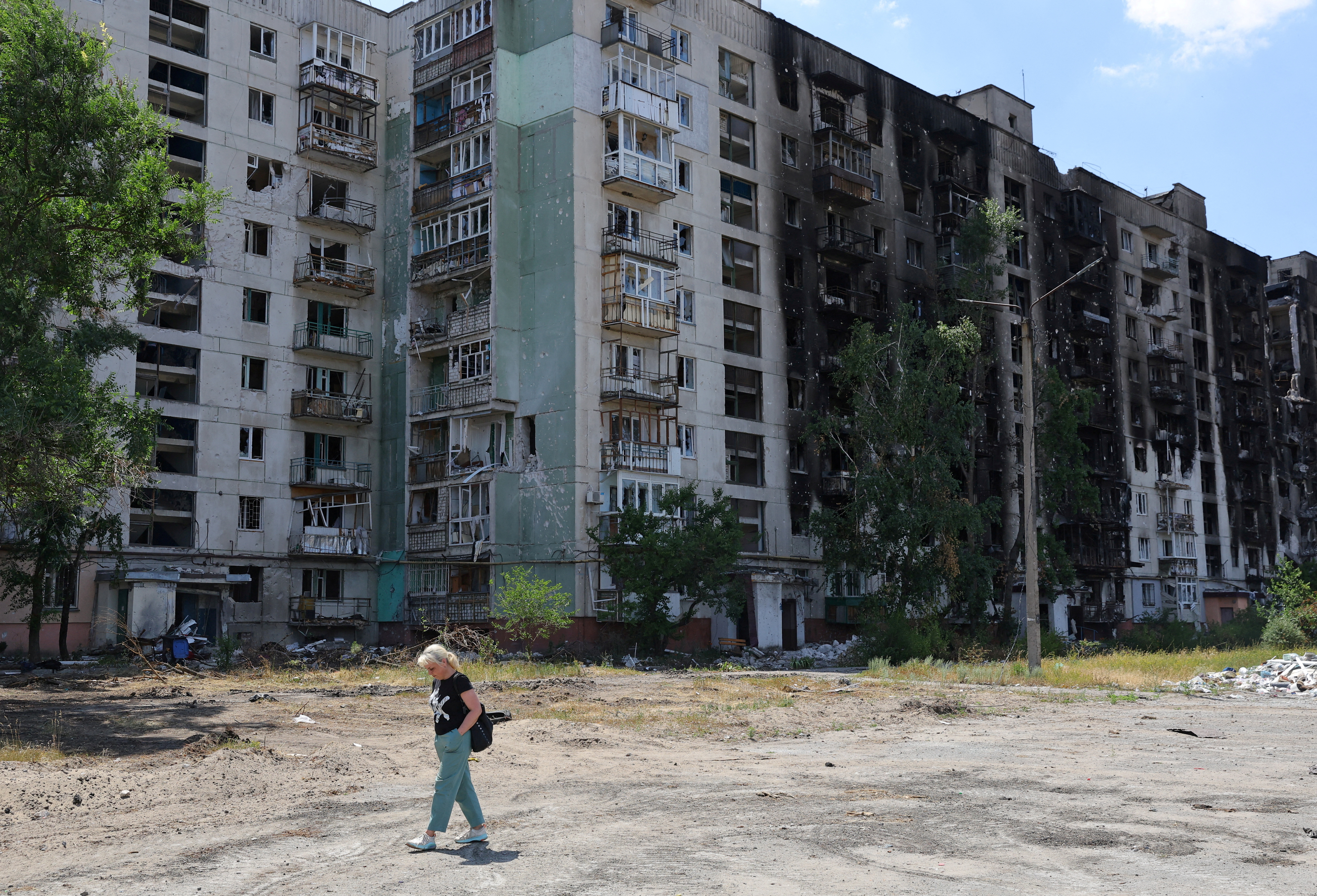 A local resident walks past a heavily damaged apartment building in Sievierodonetsk