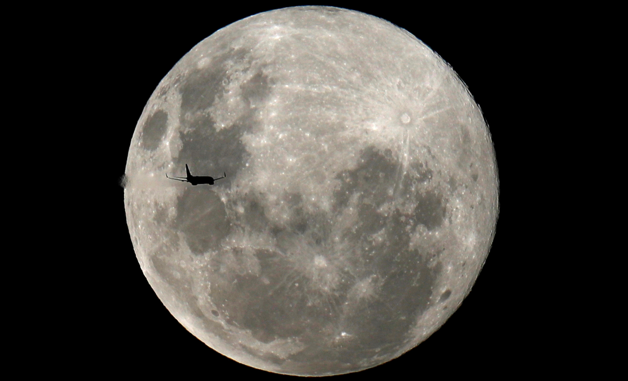 A plane is pictured in front of the full moon in Curitiba