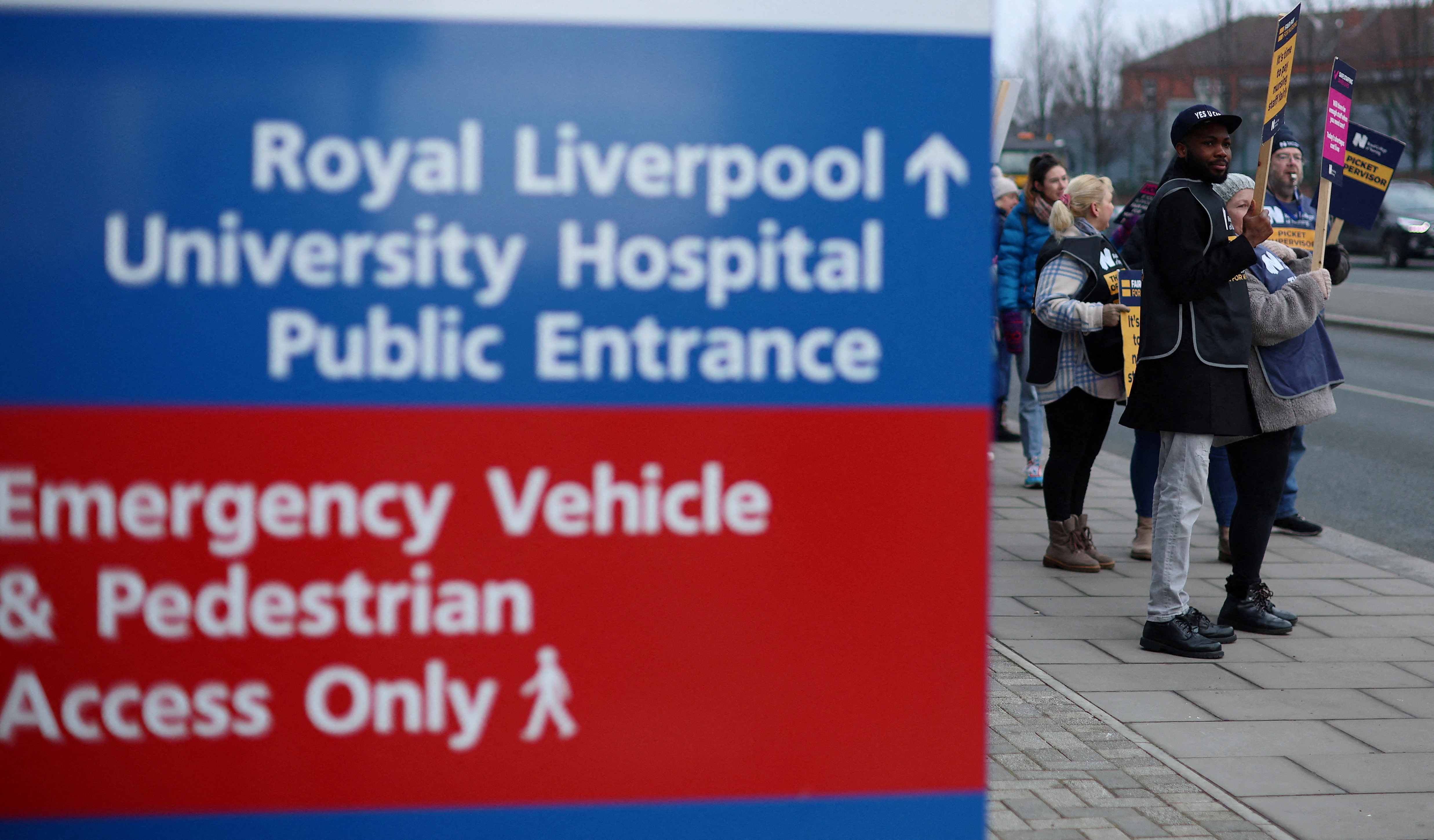 La gente sostiene pancartas mientras se paran en una línea de piquete durante una huelga de trabajadores médicos del NHS, en medio de una disputa con el gobierno sobre los salarios, fuera del Royal Liverpool University Hospital en Liverpool.