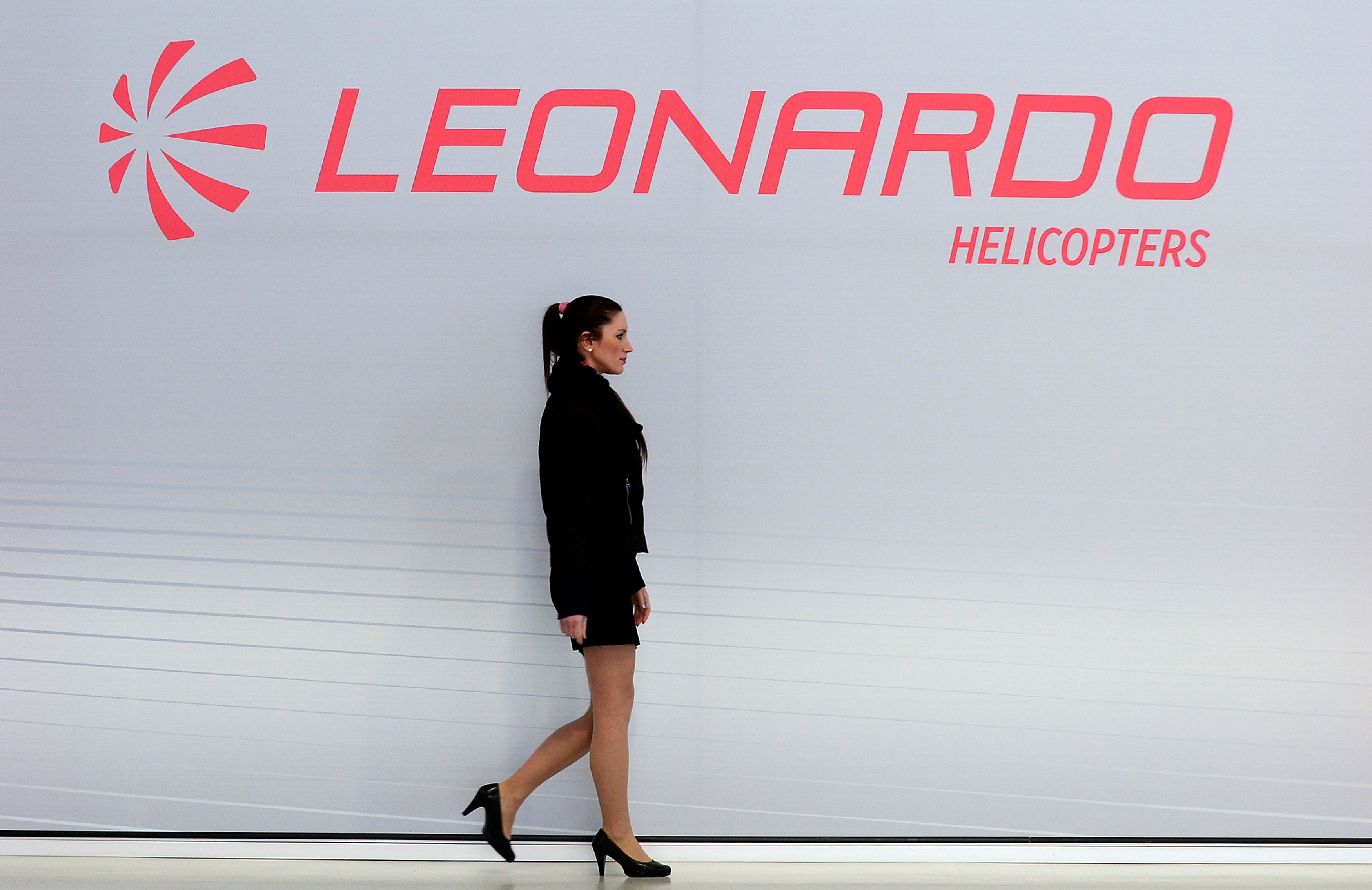 A hostess walks past a Leonardo's helicopters logo at the headquarters in Vergiate
