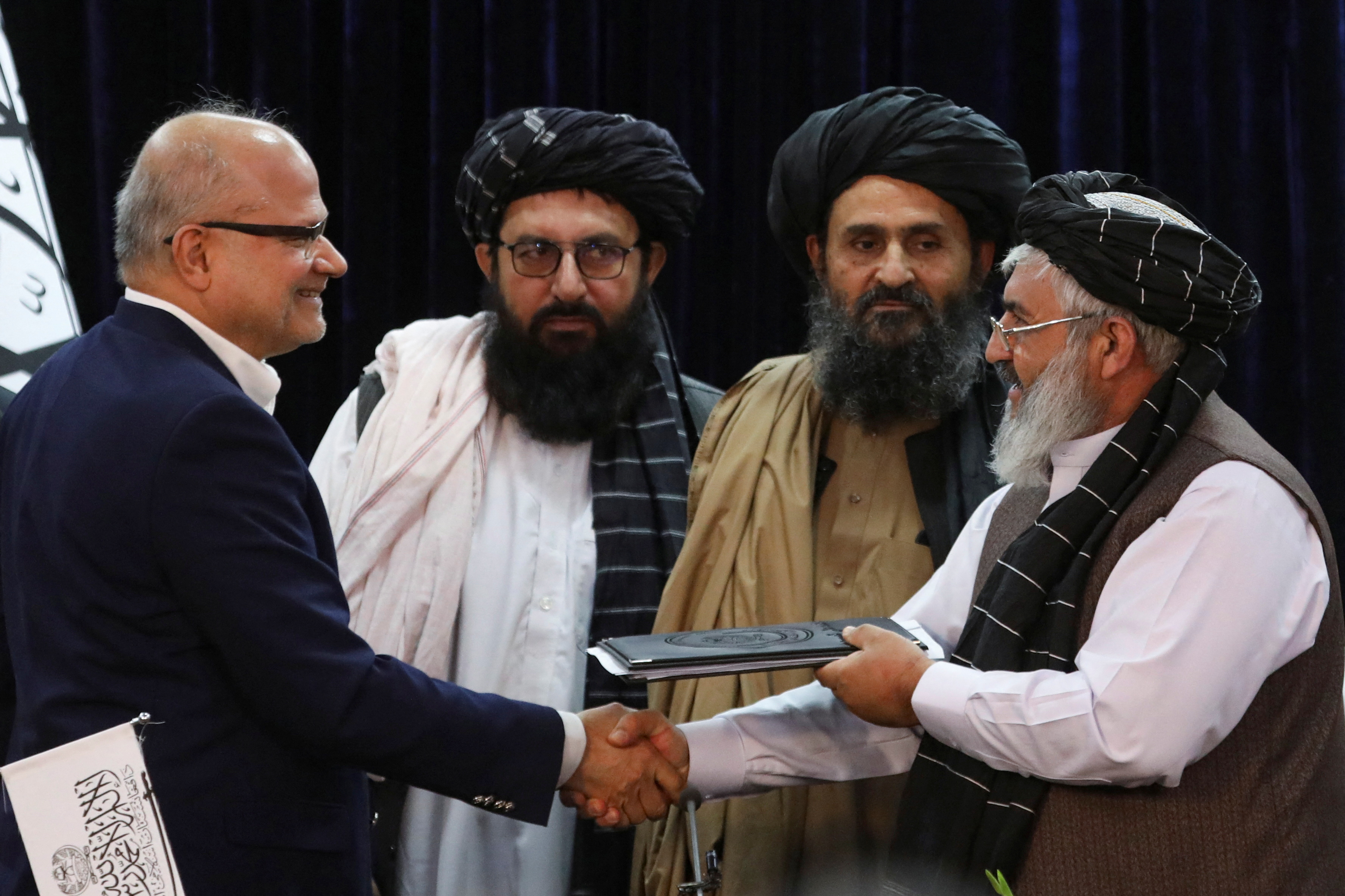 UAE chief financial officer of GAAC firm, and Deputy Ministry of Transport and Taliban's Deputy Head of Civil Aviation of Afghanistan, exchange documents, in Kabul