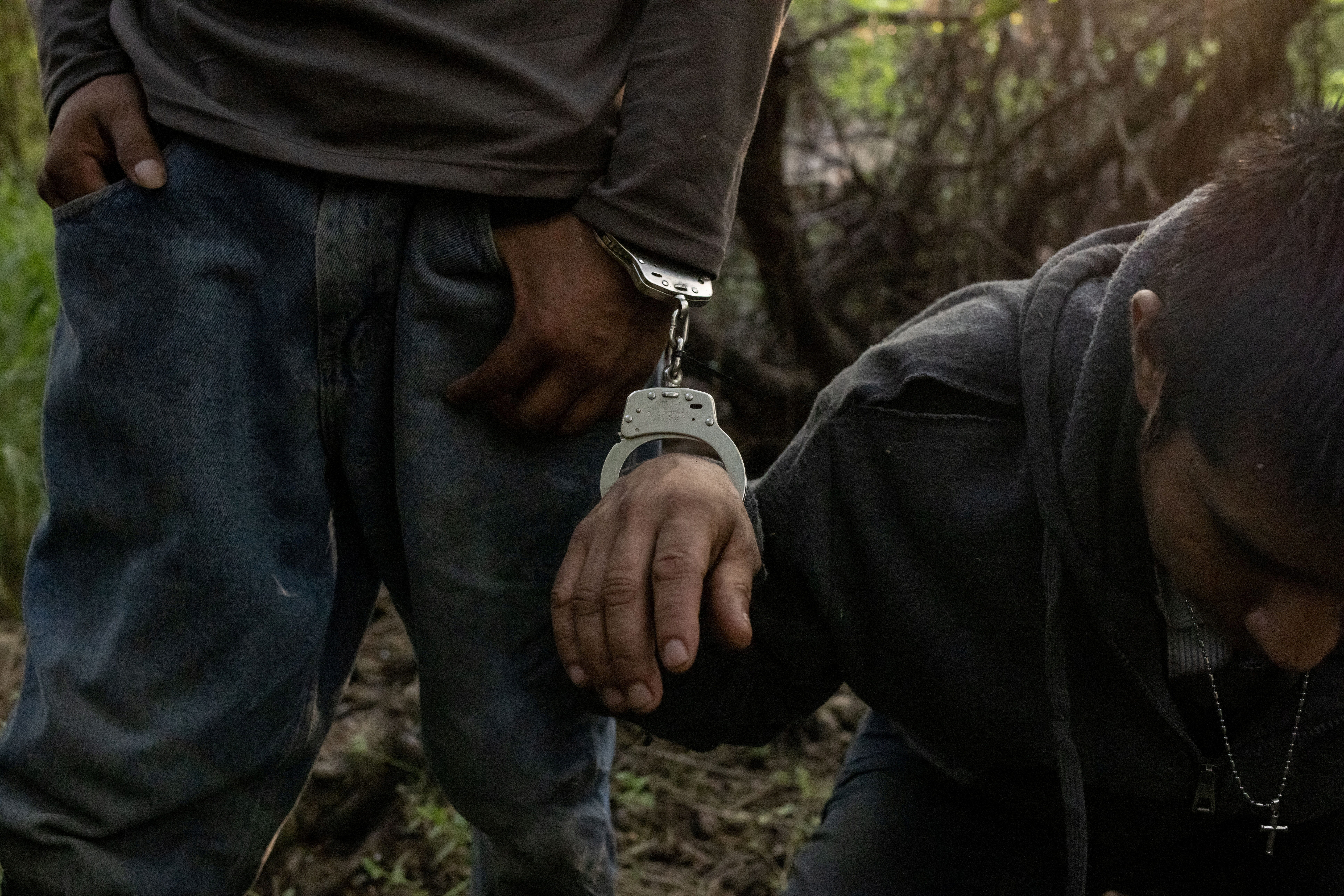 Migrant from Guatemala sits handcuffed after crossing into Texas from Mexico
