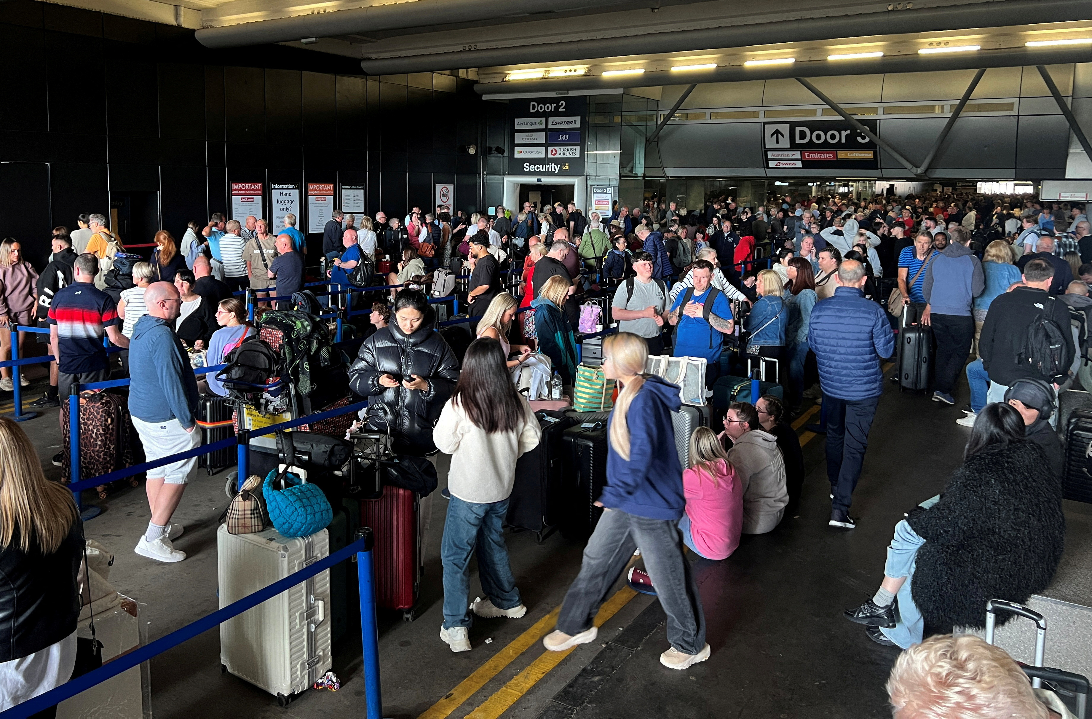 Passengers queue outside Terminal 1 after an overnight power cut led to disruptions and cancellations at Manchester Airport in Manchester