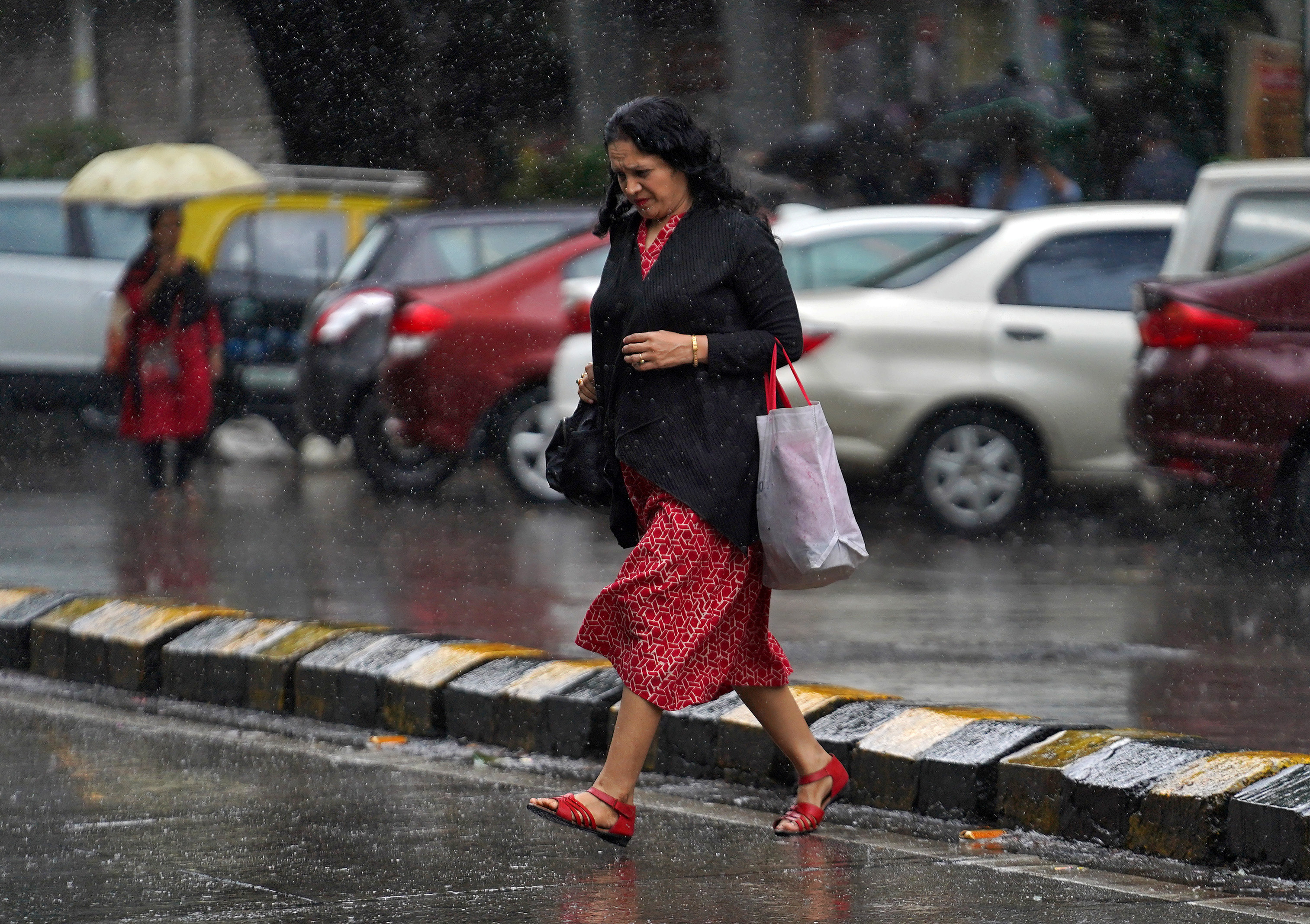 A woman crosses a road as it rains in Mumbai