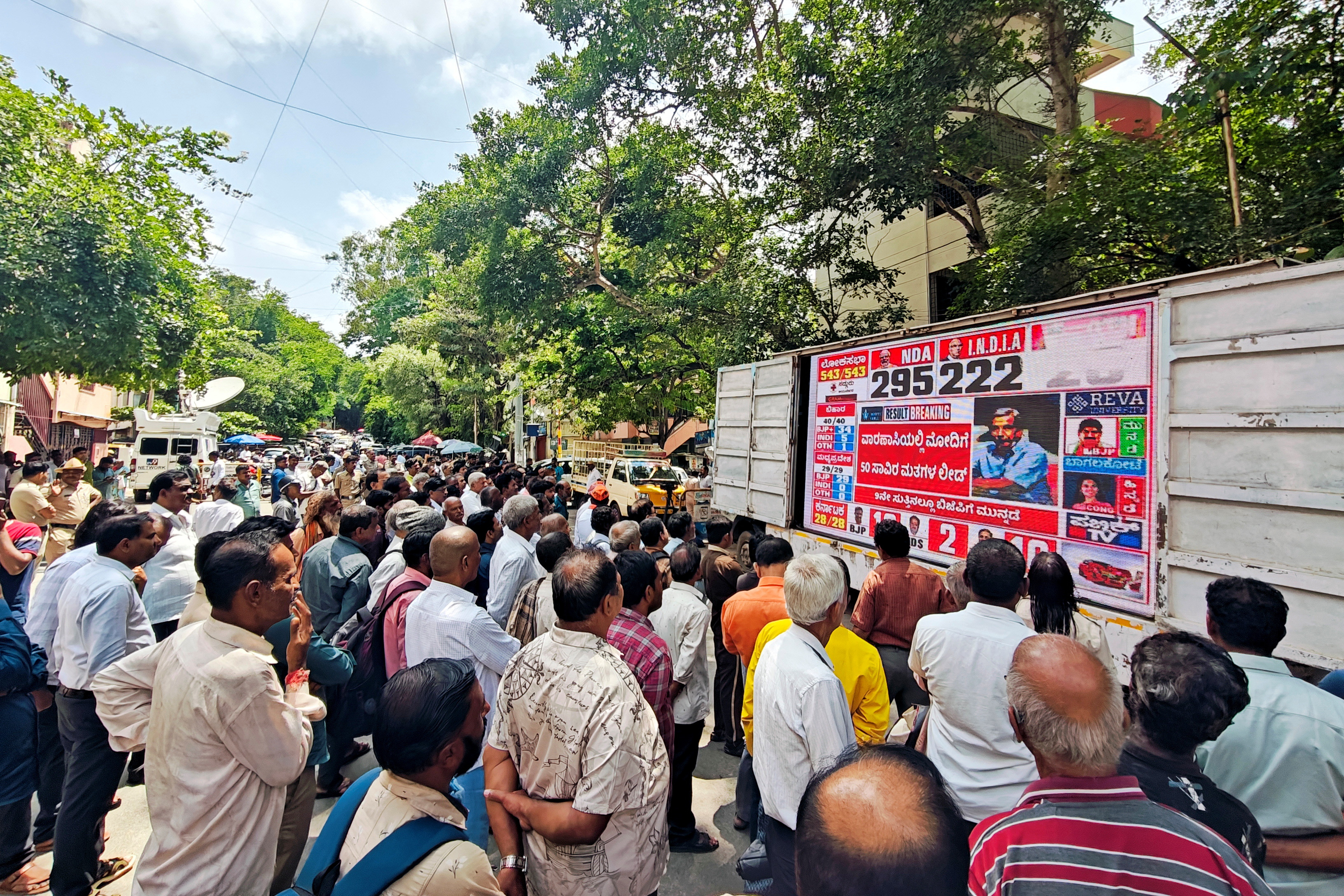 Supporters of the Bharatiya Janata Party watch a screen showing initial poll results outside its party office in Bengaluru