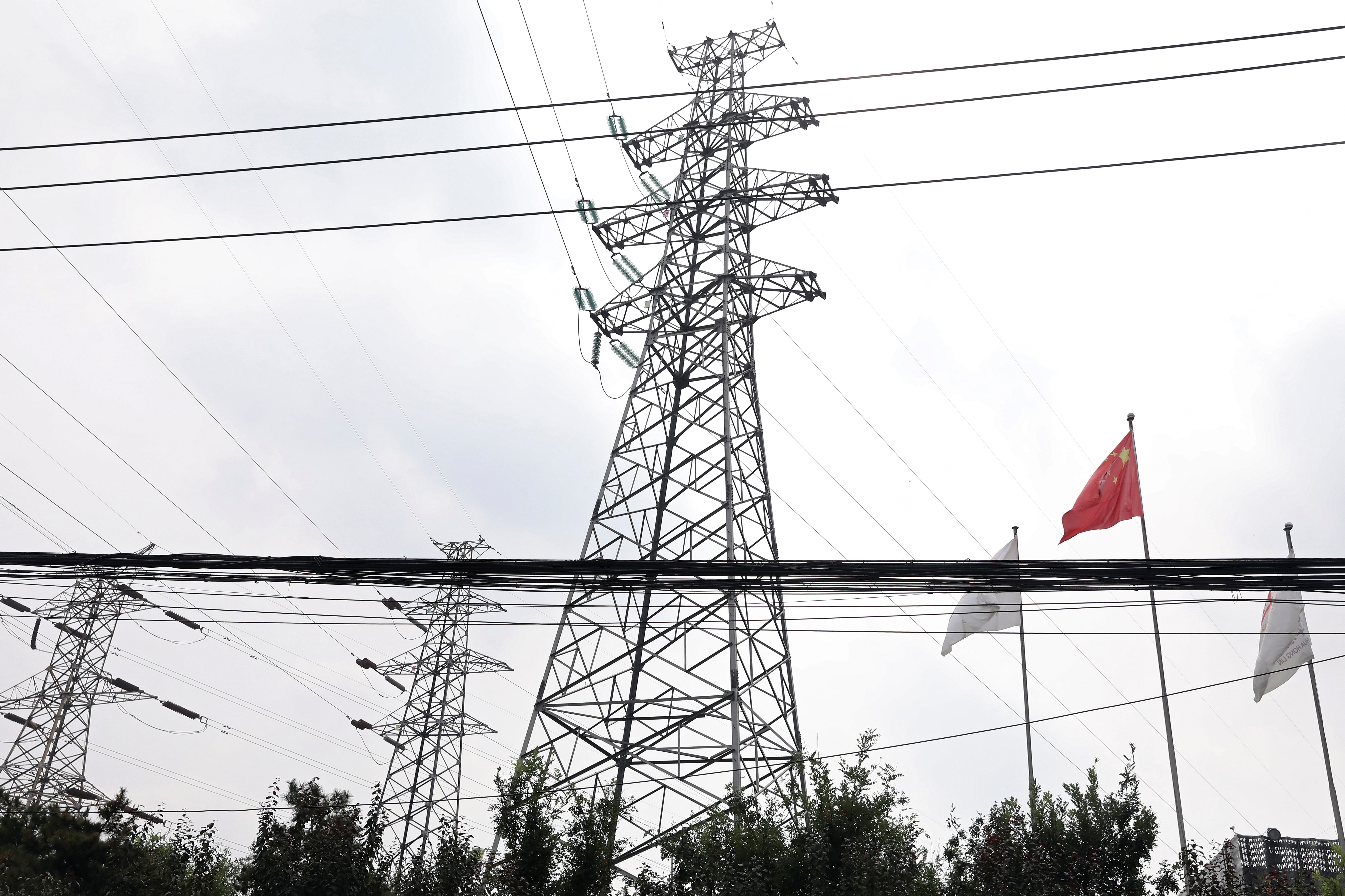 Chinese flag flutters near power lines and electricity towers in Beijing
