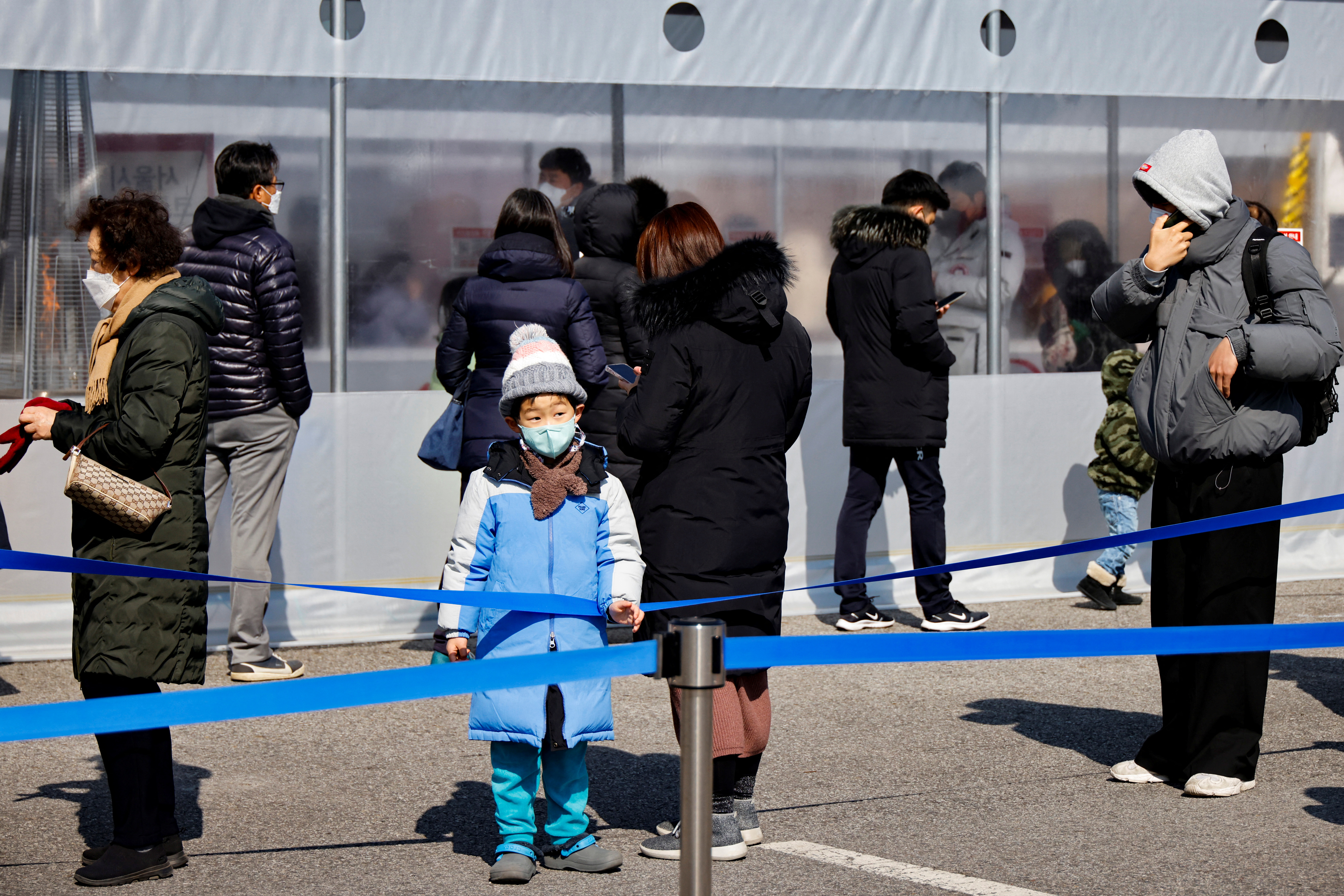People wait in line to undergo the COVID-19 test at a temporary testing site set up in Seoul