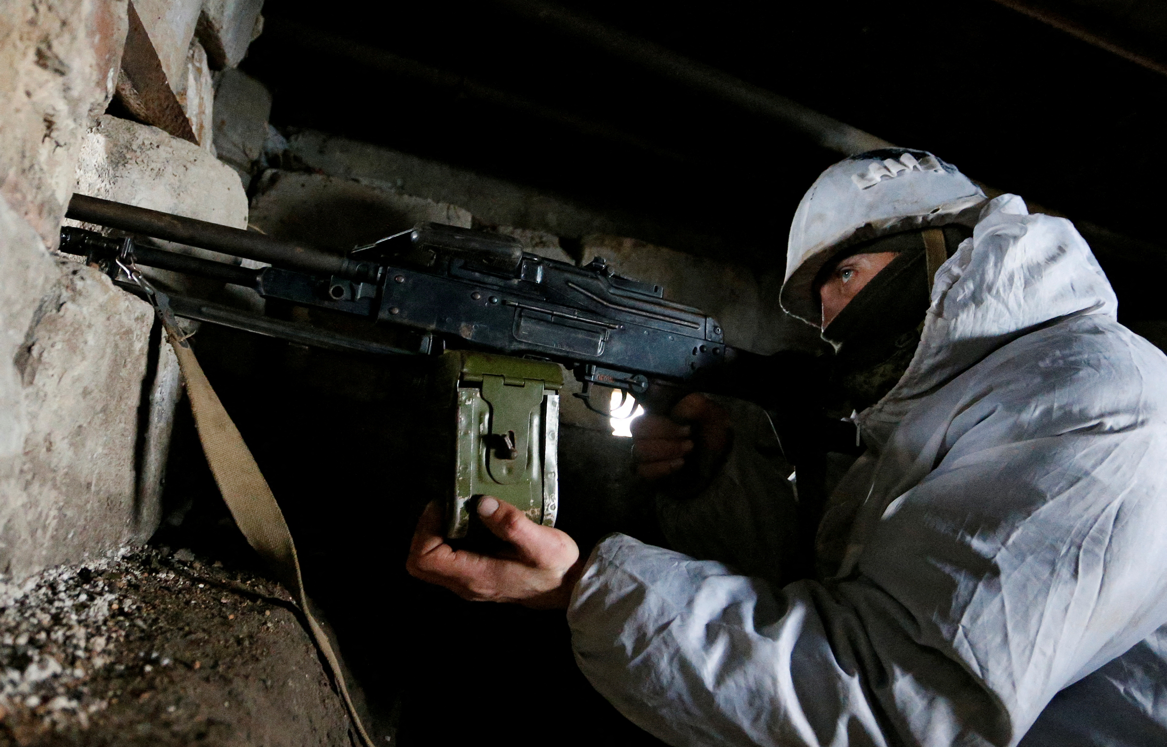 A militant of the self-proclaimed Luhansk People's Republic points a weapon at fighting positions in Luhansk Region