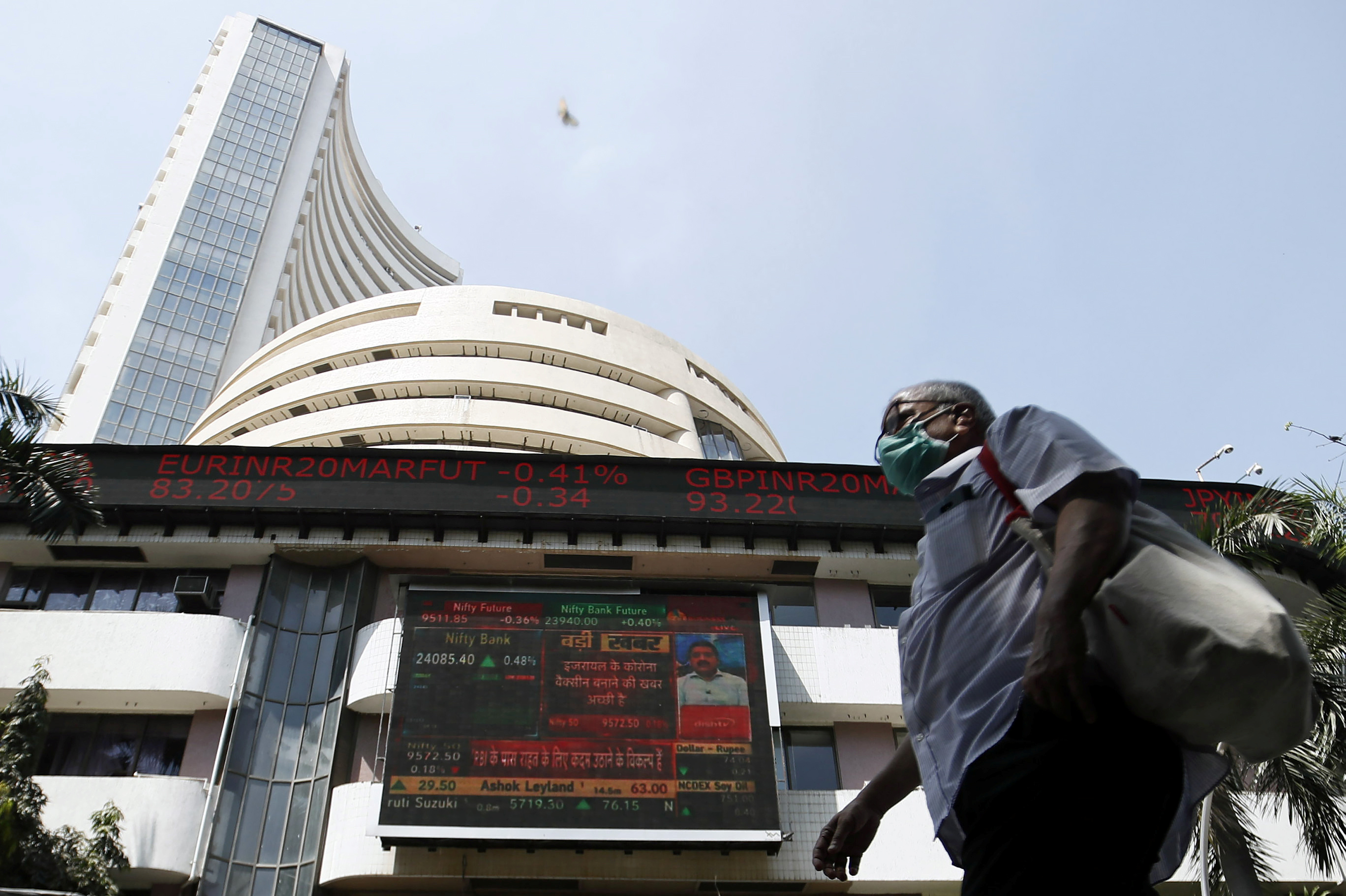 A man wearing a protective mask walks past the Bombay Stock Exchange (BSE) building in Mumbai