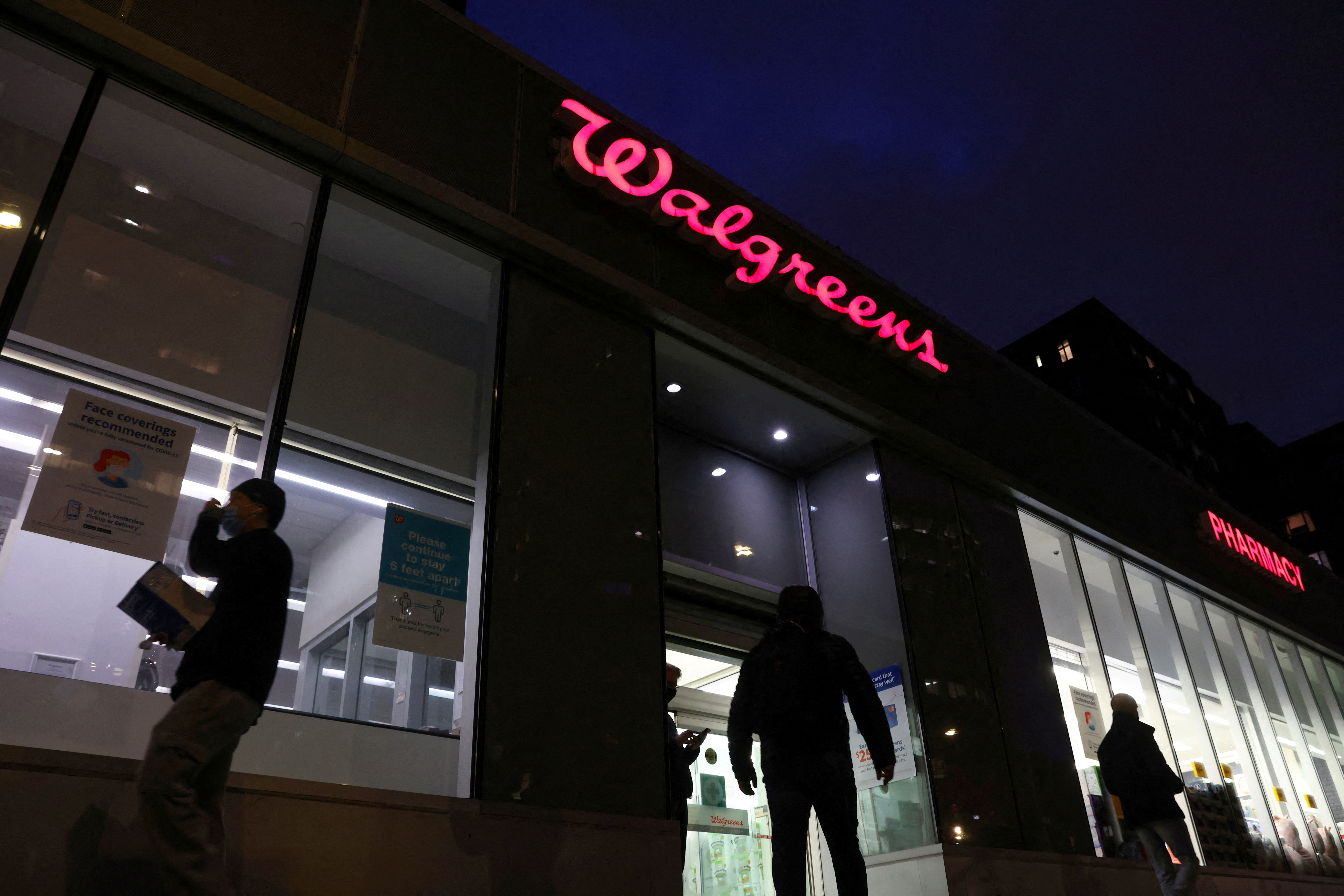 People walk by a Walgreens, owned by the Walgreens Boots Alliance, Inc., in Manhattan, New York City, U.S., November 26, 2021. REUTERS/Andrew Kelly