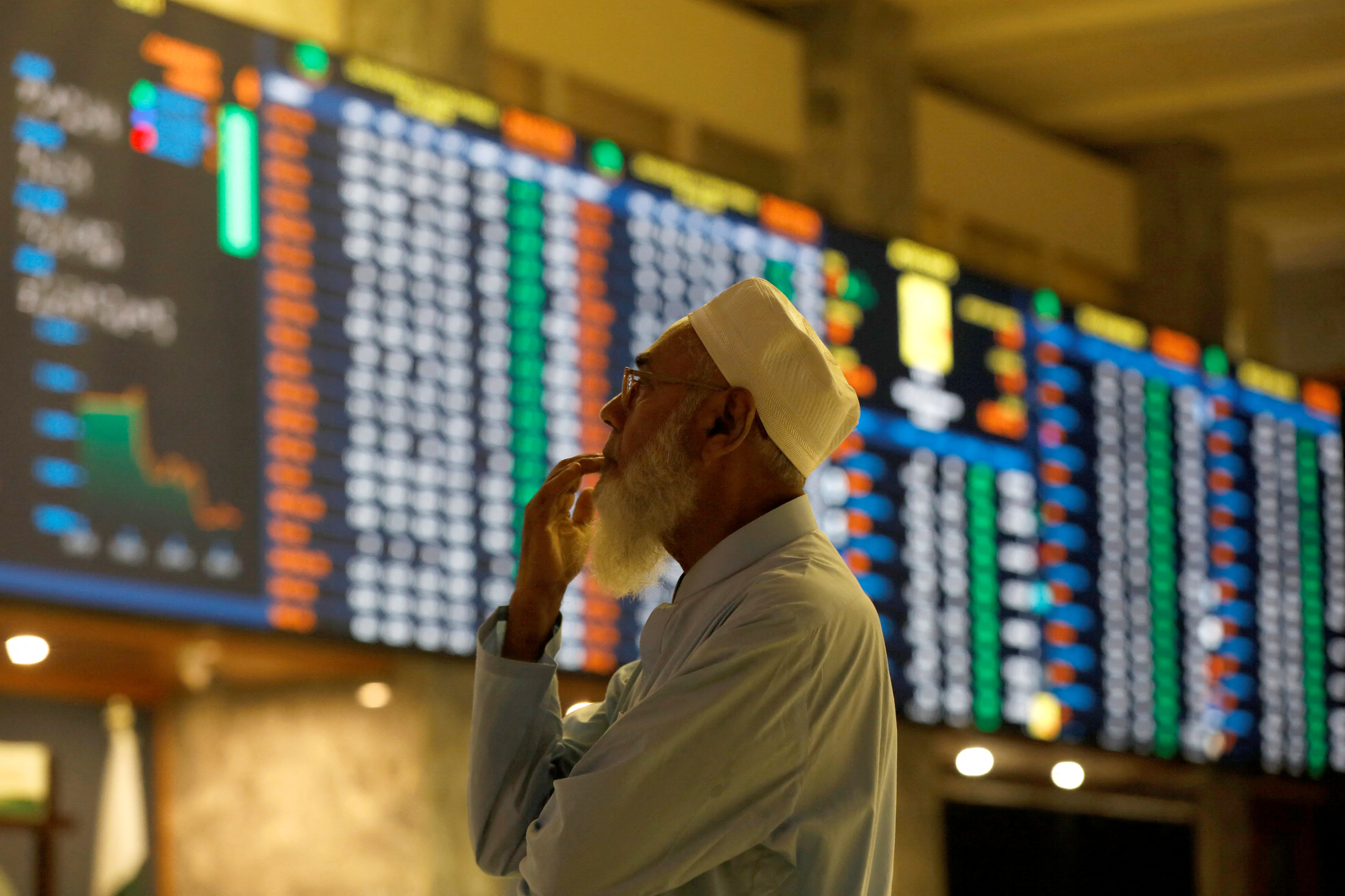 Stock broker monitors the market on the electronic board displaying share prices  at the Pakistan Stock Exchange, in Karachi
