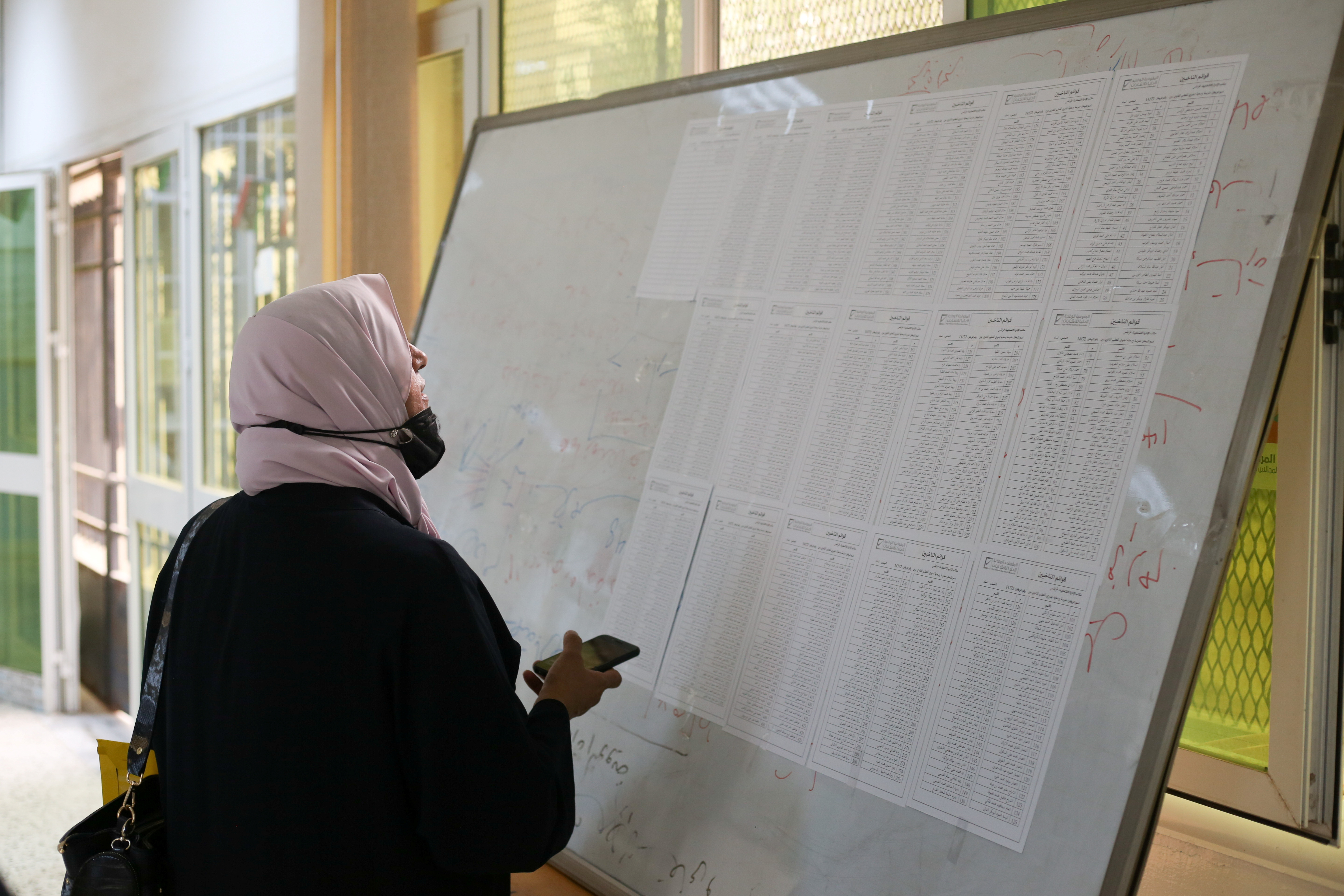 Woman checks names to receive her electoral card inside a polling station in Tripoli