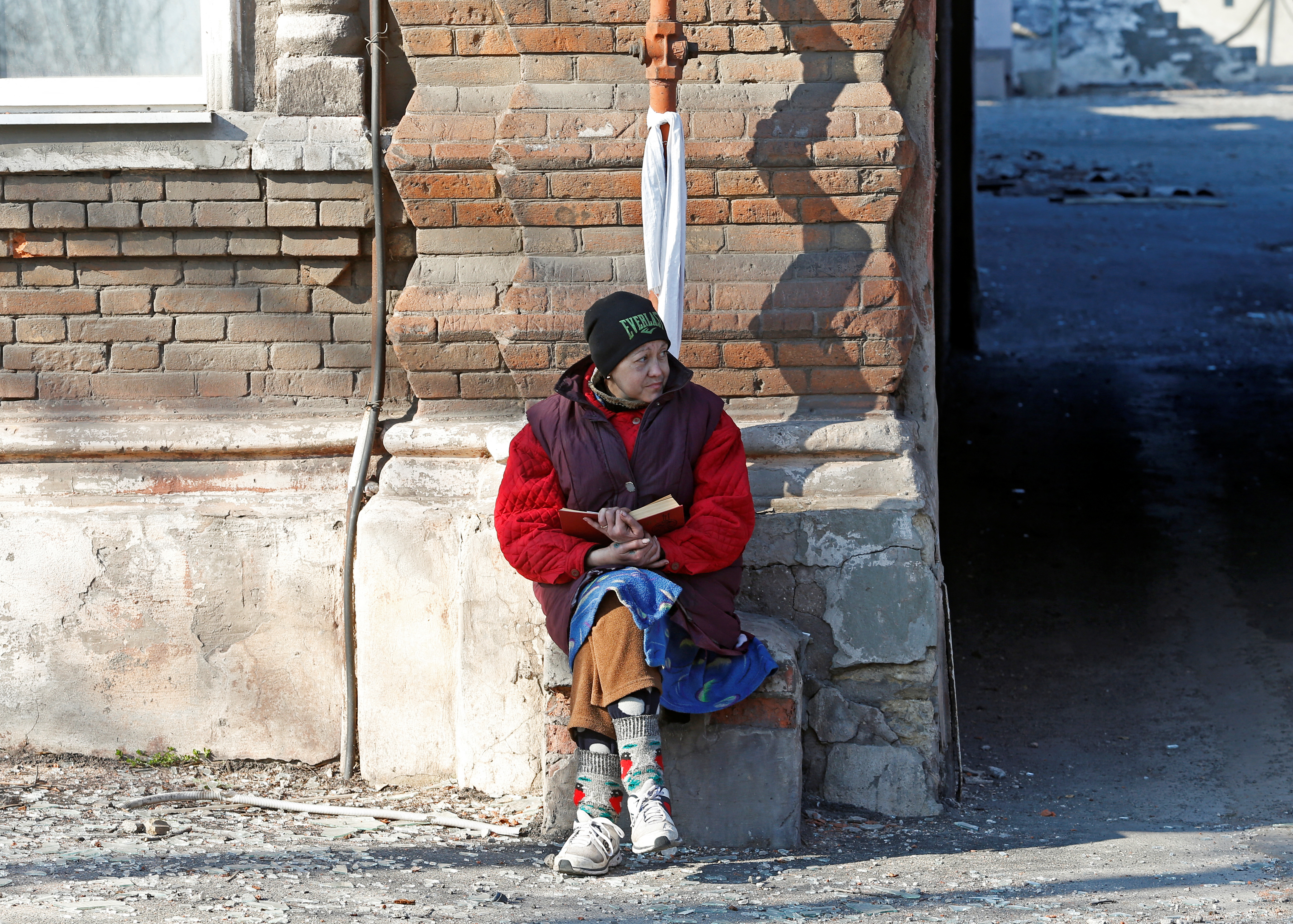 A local resident sits outside a house in Mariupol