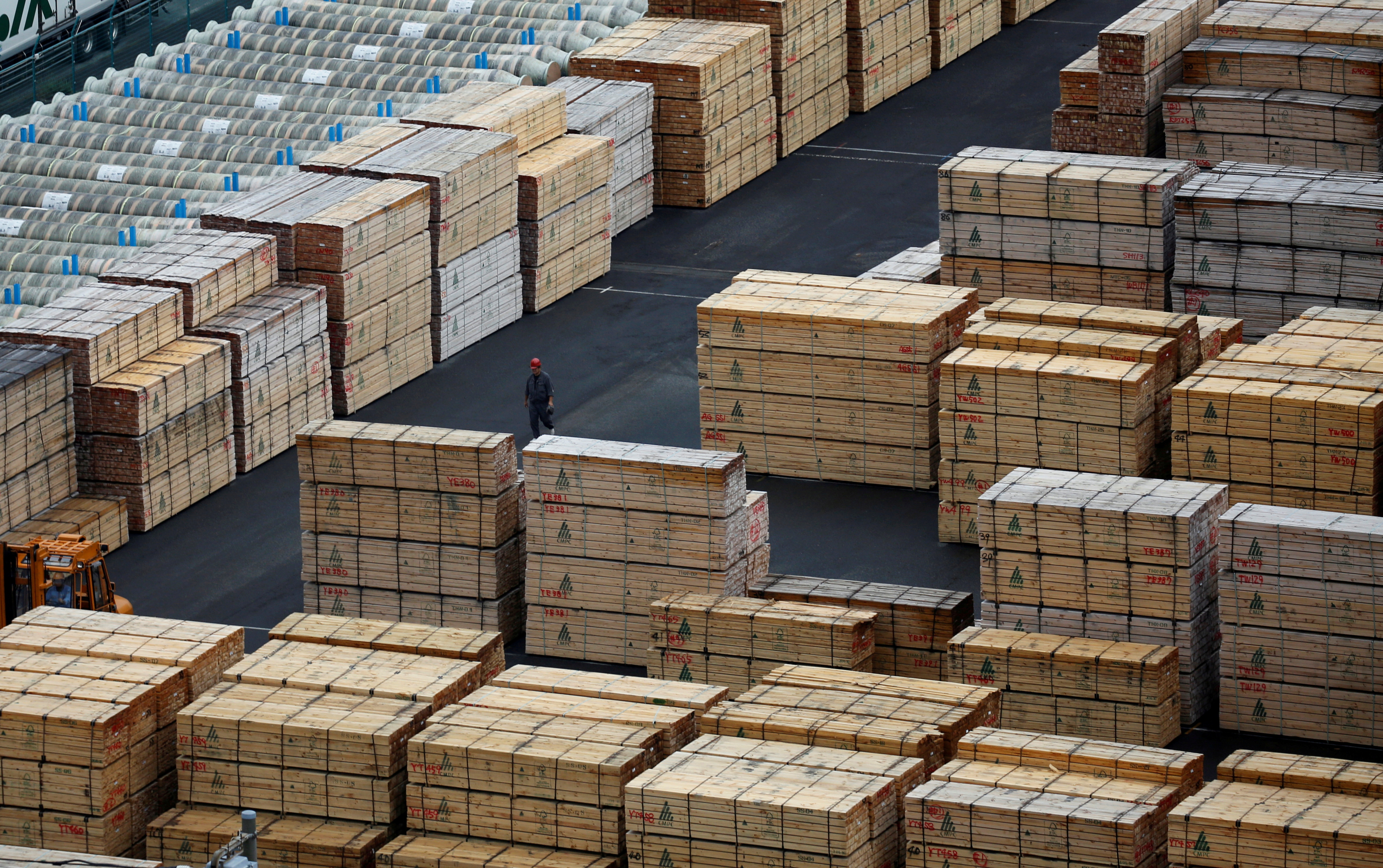 Worker walks among processed timber at a port in Keihin industrial zone in Kawasaki