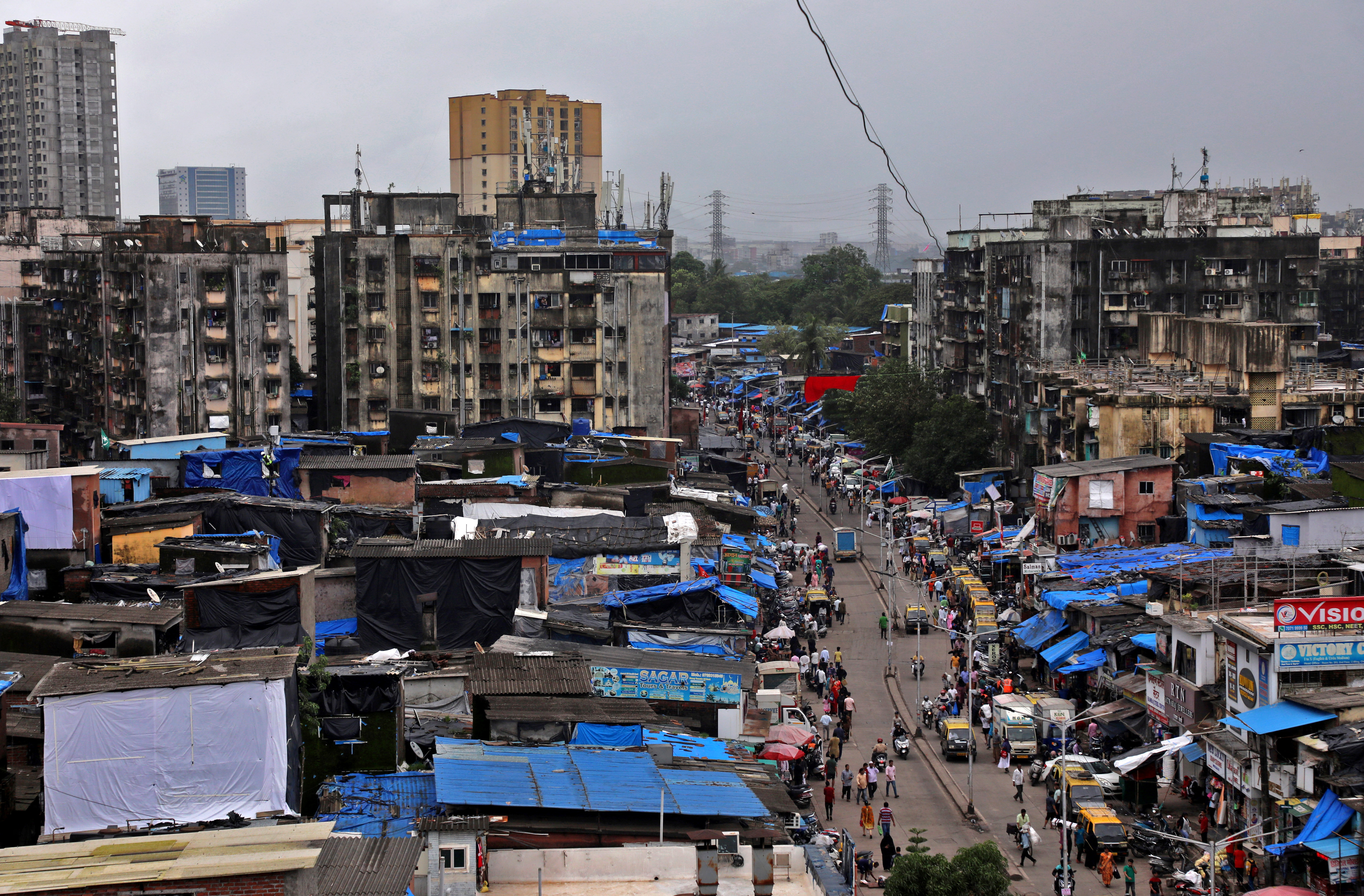 People and vehicles move past shanties in Dharavi, Mumbai