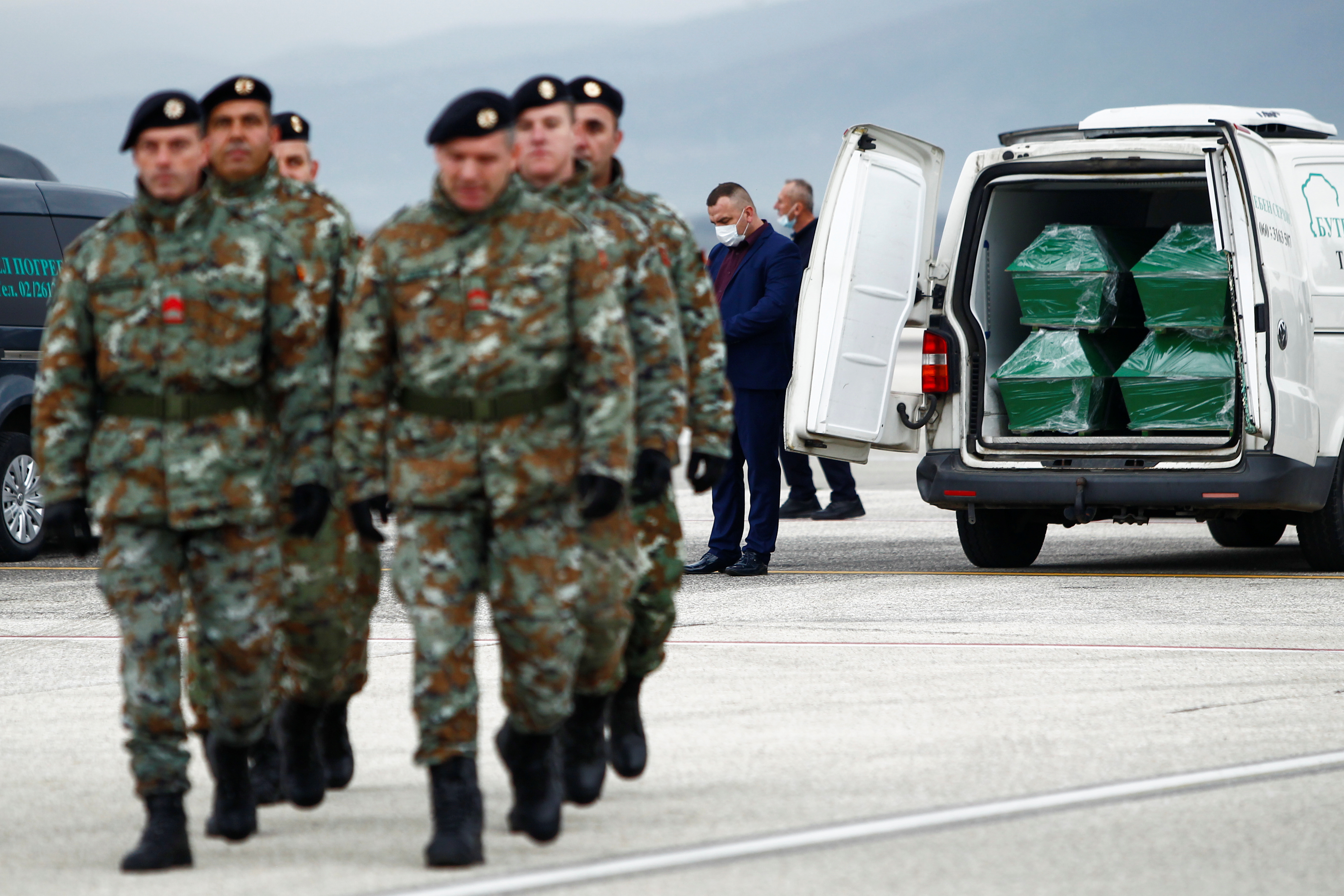 Soldiers walk past as coffins of the victims of last week's deadly bus crash in Bulgaria, sit into a vehicle after their arrival at the Skopje Airport, North Macedonia December 3, 2021. REUTERS/Ognen Teofilovski