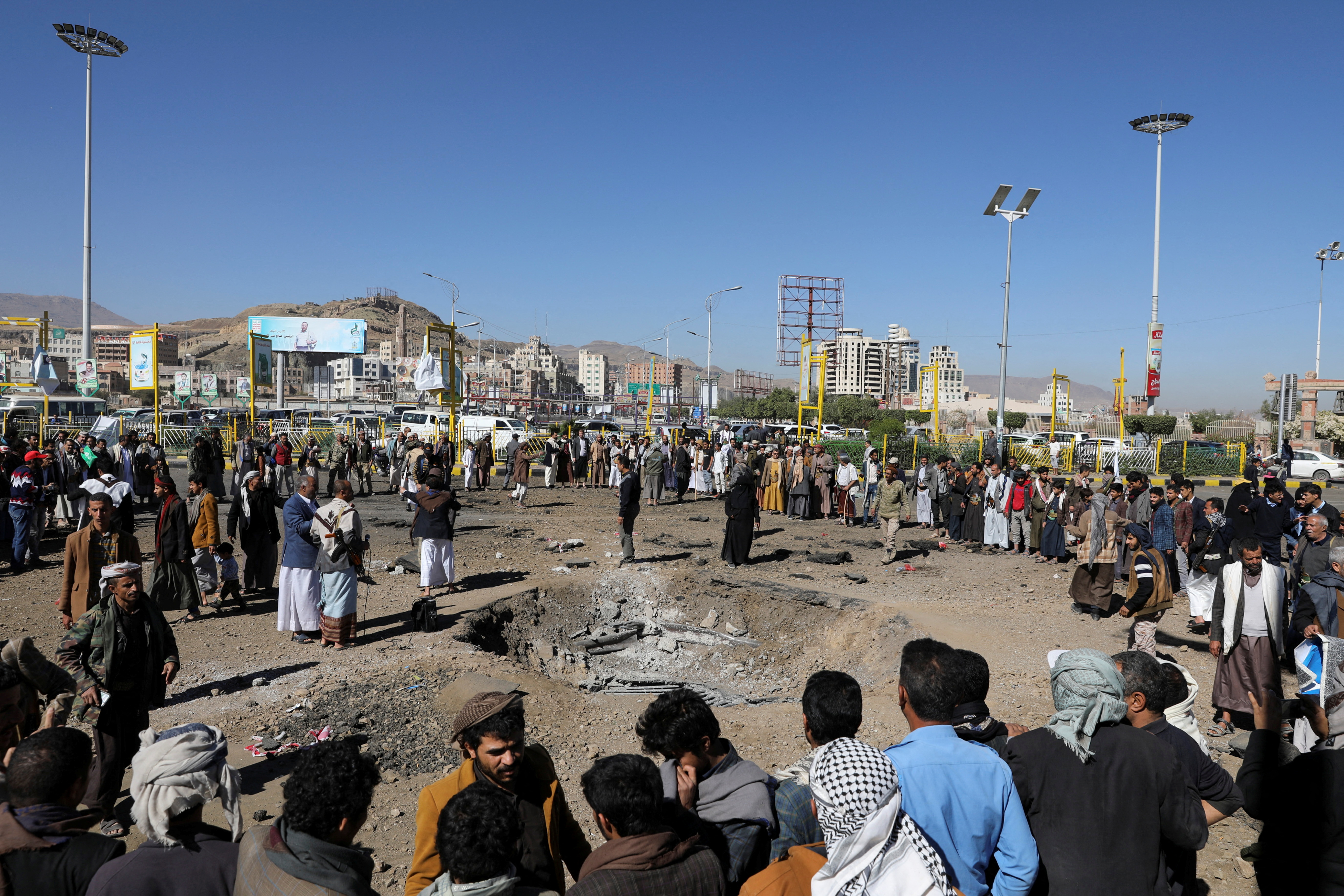 People gather around a crater caused by a Saudi-led airstrike on a road in Sanaa, Yemen, December 23, 2021. REUTERS/Khaled Abdullah