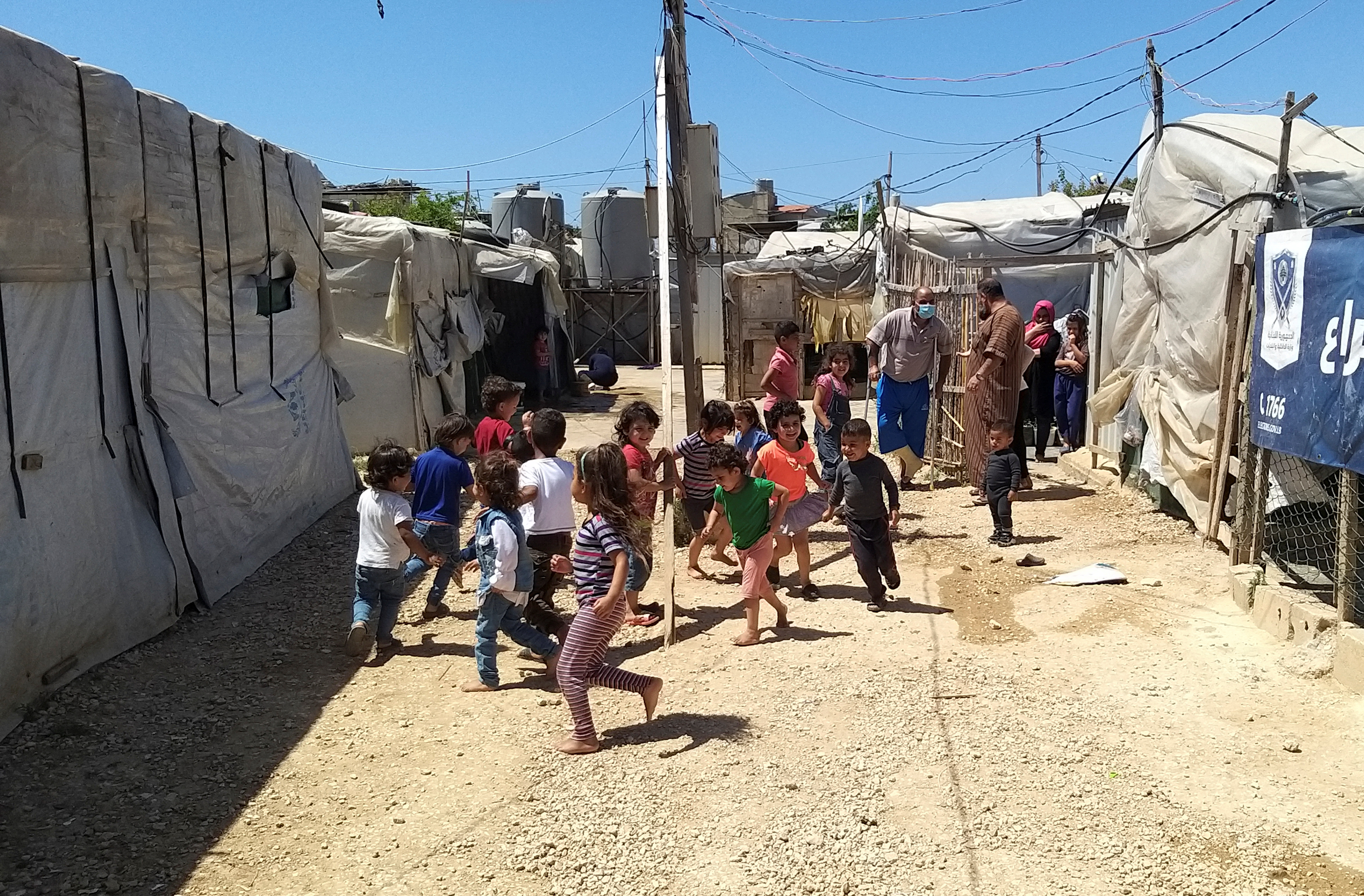 Syrian refugee children run together near tents at an informal tented settlement in Akkar