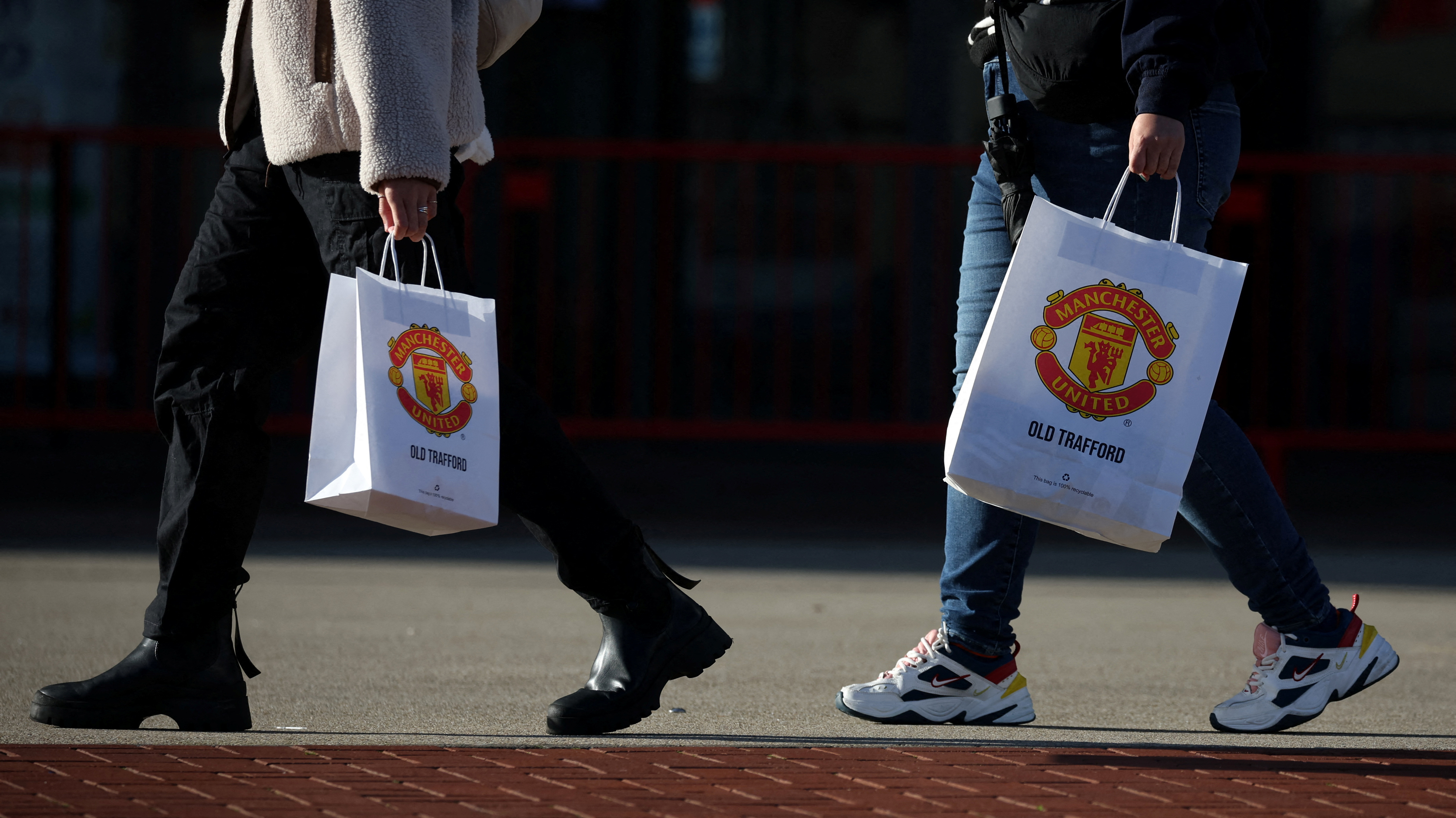 People with Manchester United bags outside Old Trafford stadium
