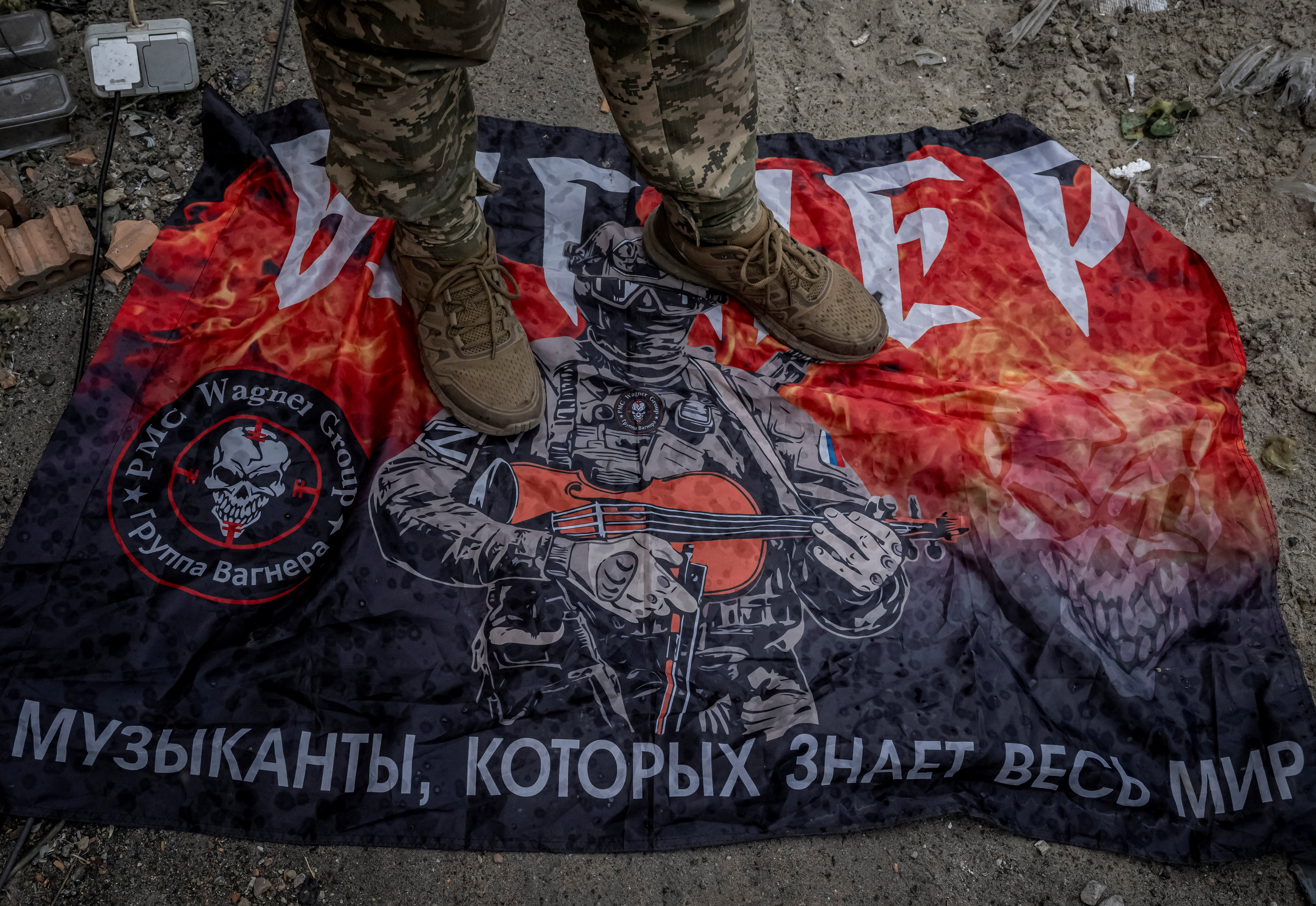 A Ukrainian serviceman stands on Wagner flag near the Russian border in Sumy region