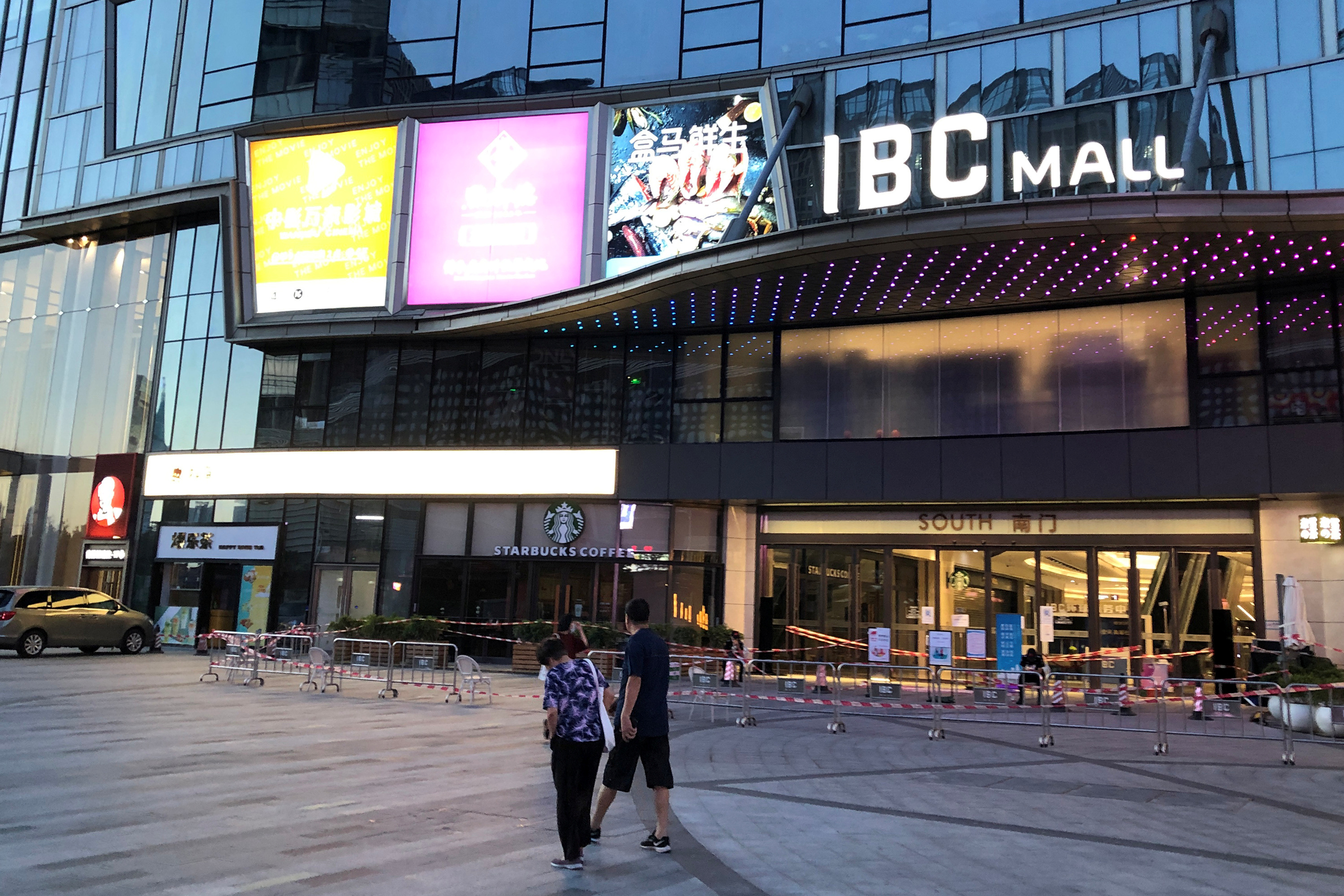 People wearing face masks walk past Shenzhen's IBC Mall