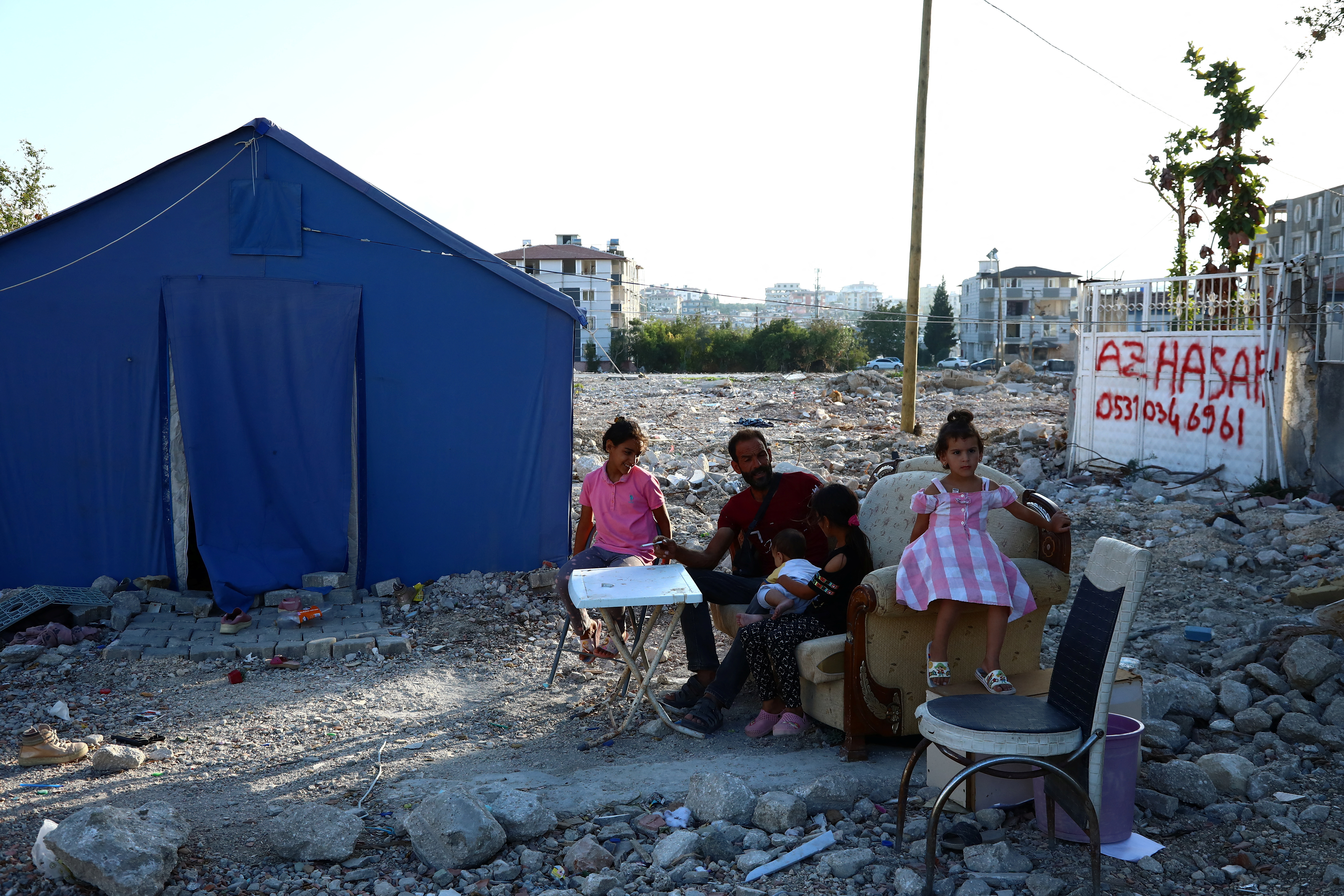 Ammar, a Syrian earthquake survivor, chats with his children outside their tent in Antakya