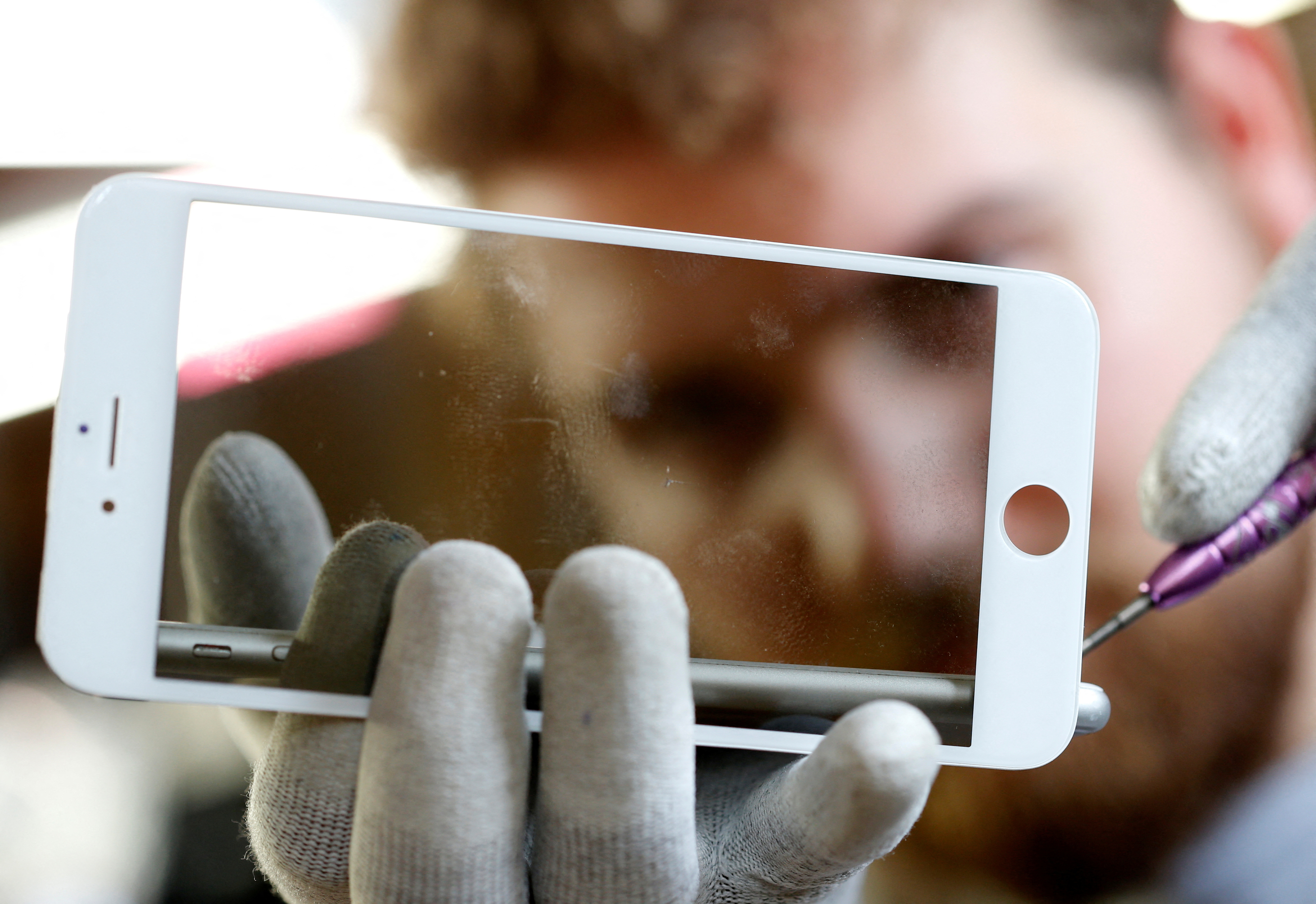 A worker refurbishes an Apple Iphone cell phone at a workshop of the Oxflo company, specialised in refurbishment of broken European smartphones in Lusignac