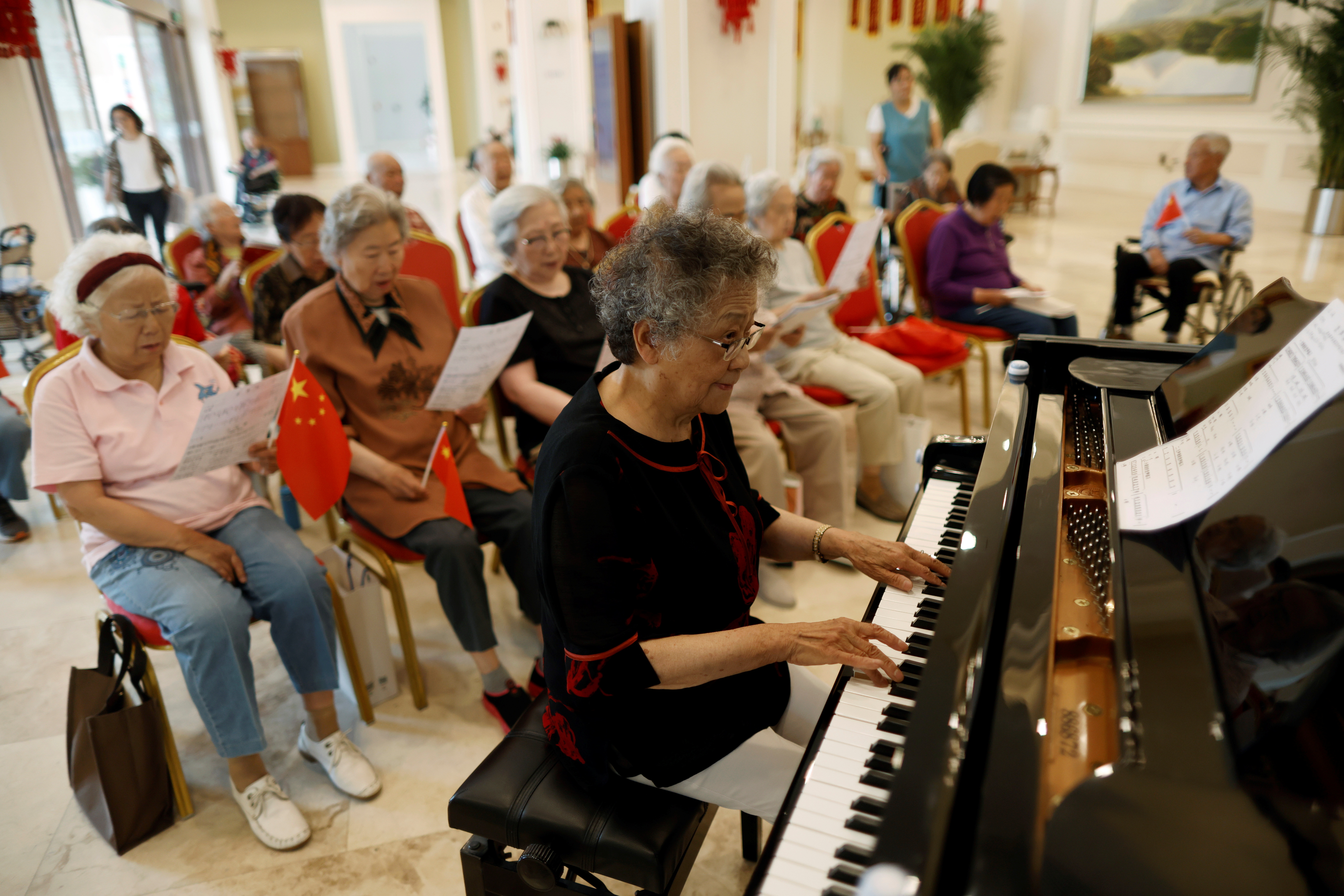 Wang plays the piano during a group singing practice at a care home for the elderly, in Beijing