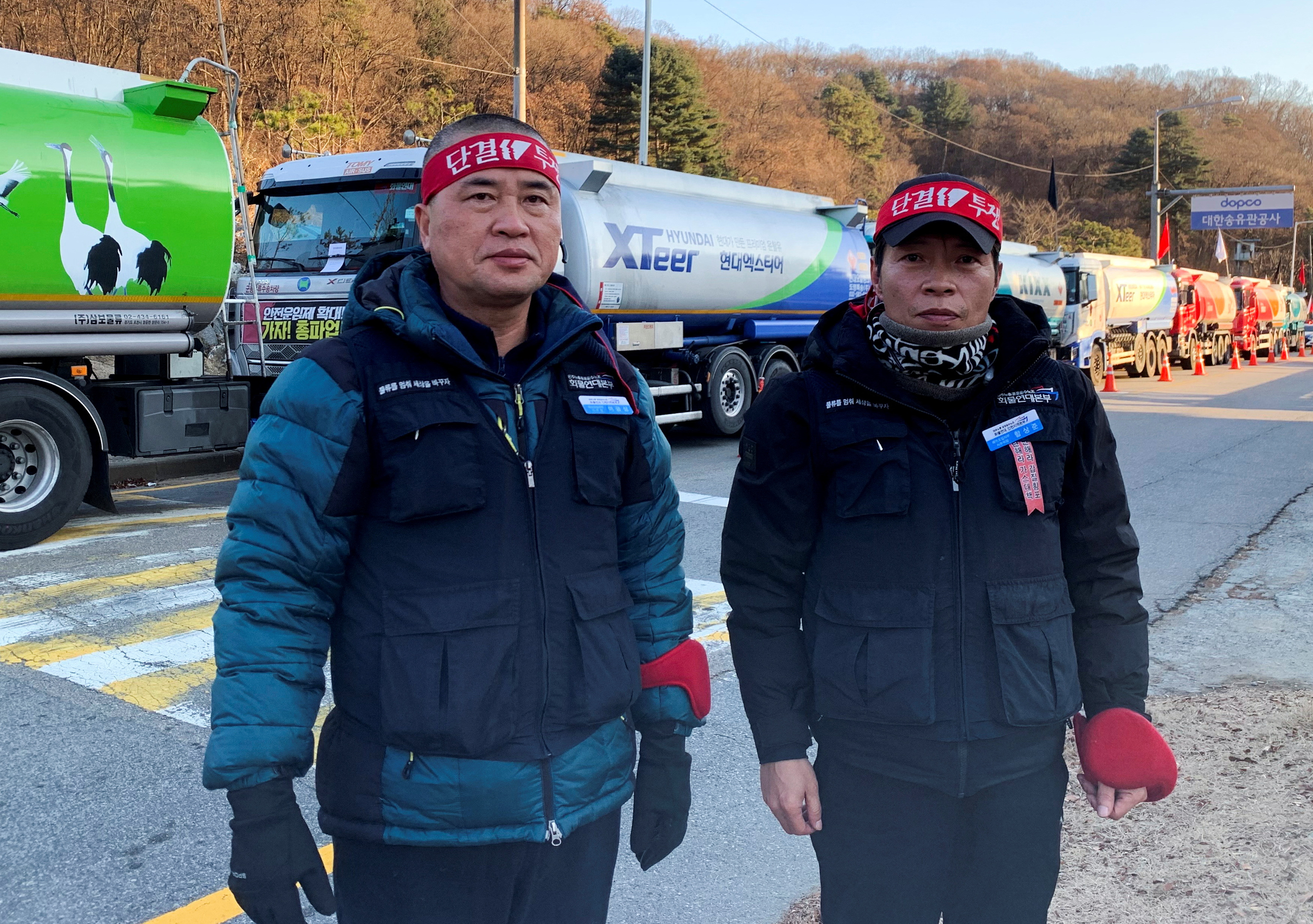 Pengemudi tank Korea Selatan yang memukau Lee Geum-sang dan Ham Sang-joon berdiri di depan truk tanker saat mereka mengambil bagian dalam pemogokan nasional di depan fasilitas penyimpanan minyak utama di Seongnam.