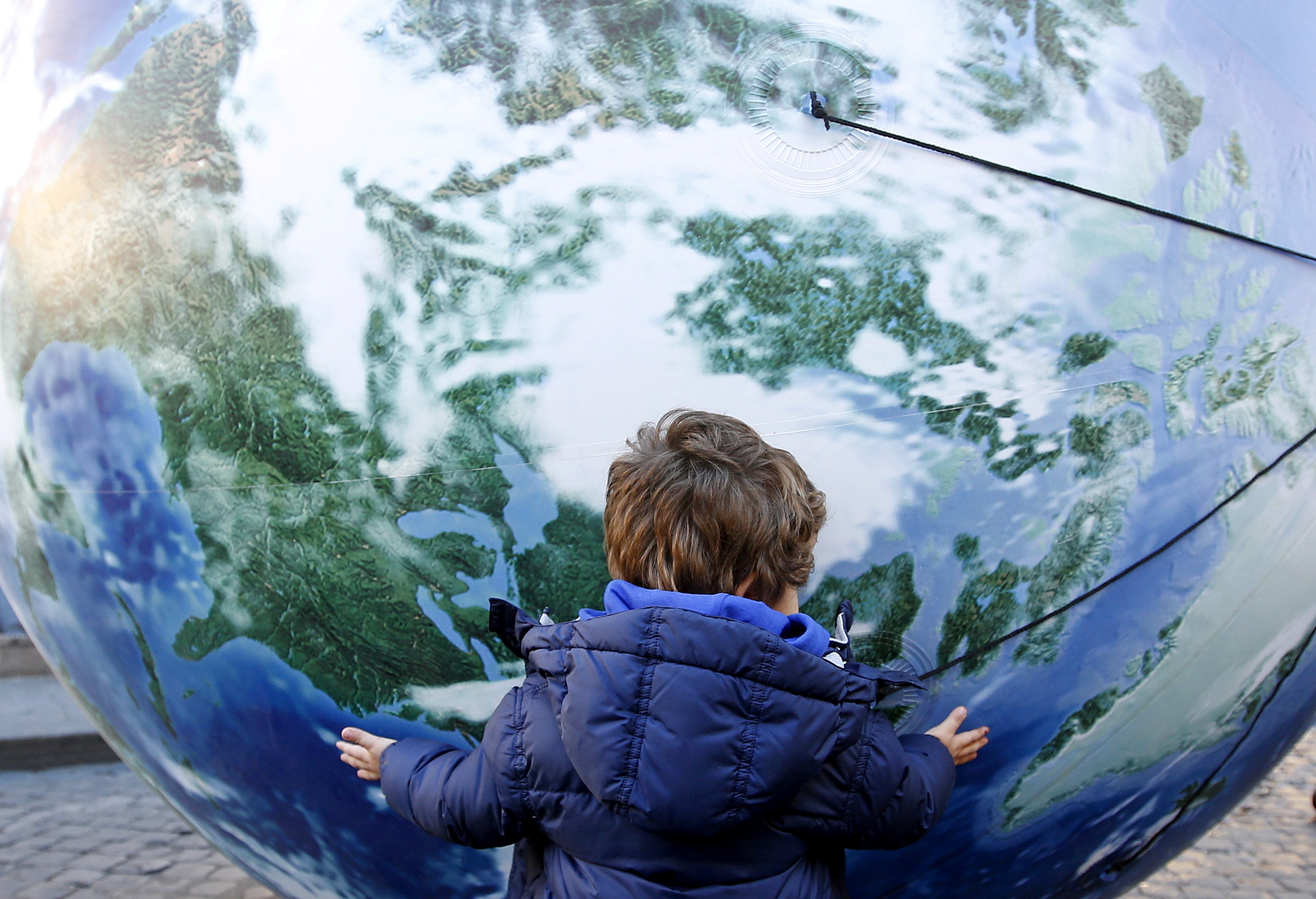 A child embraces a globe shaped balloon during a rally held ahead of the start of the 2015 Paris World Climate Change Conference, known as the COP21 summit, in Rome