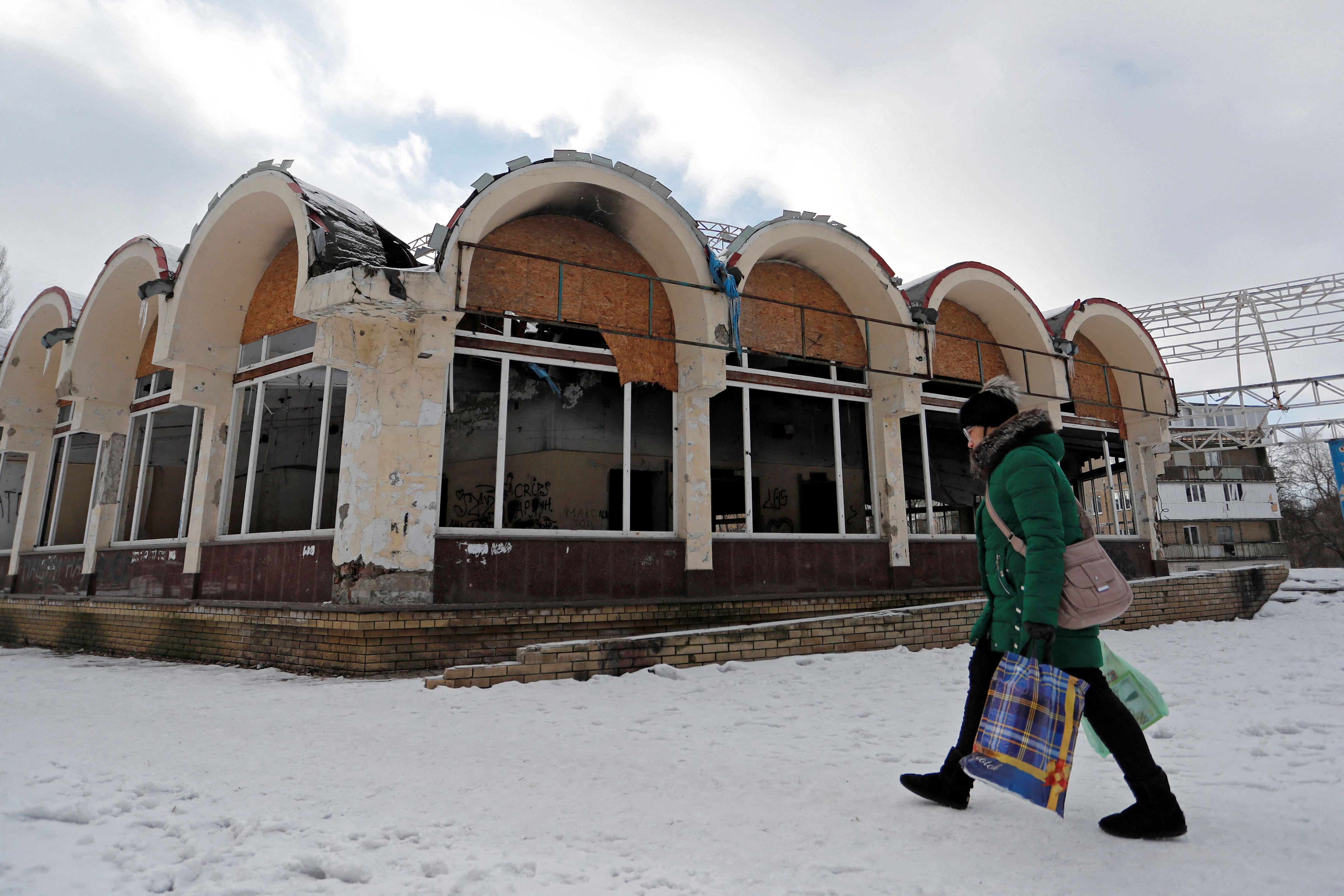 A woman walks past a damaged shop in Donetsk