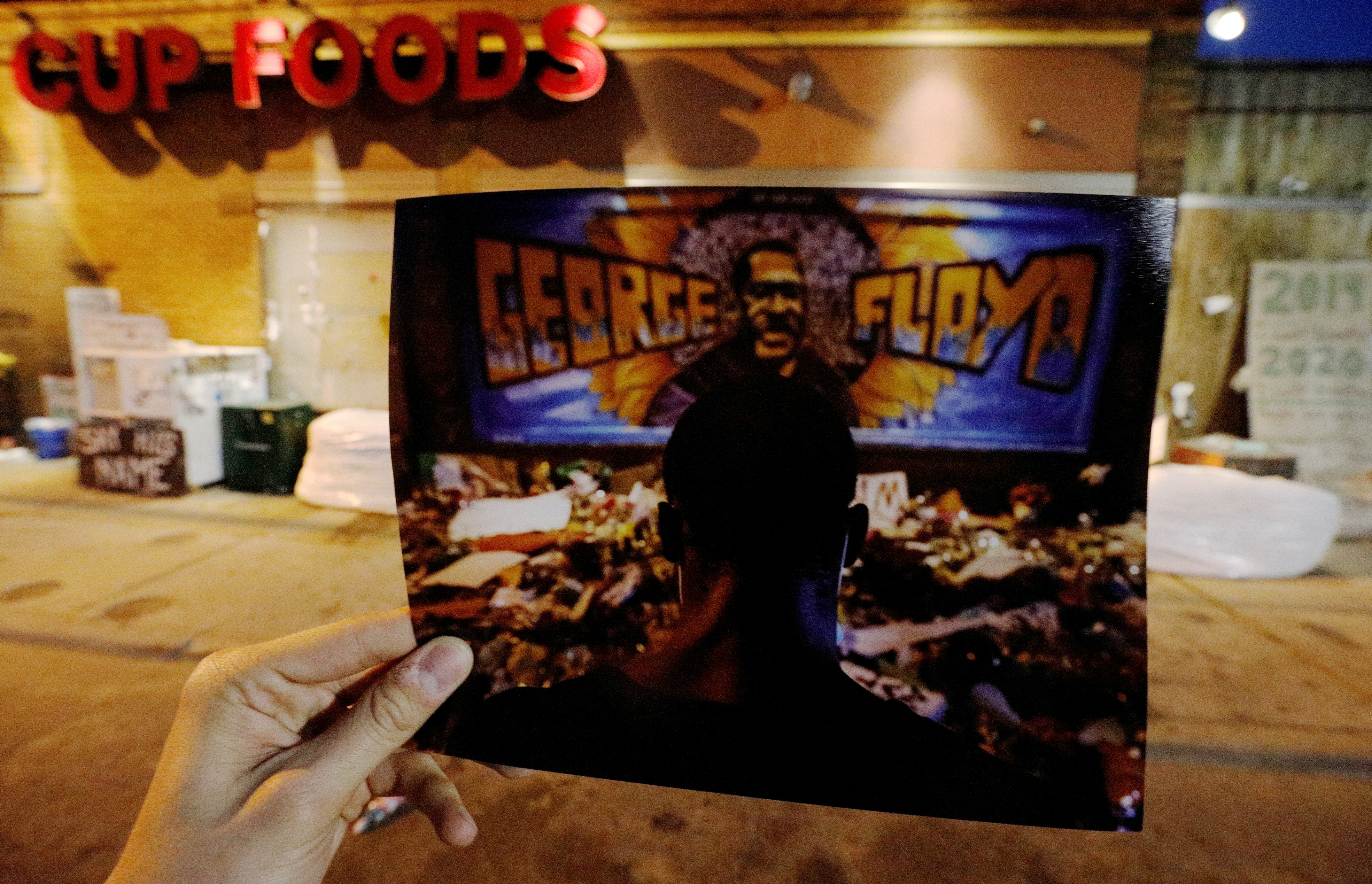 A photograph of a man reciting spoken word poetry at George Floyd Square is rephotographed in the same location in Minneapolis