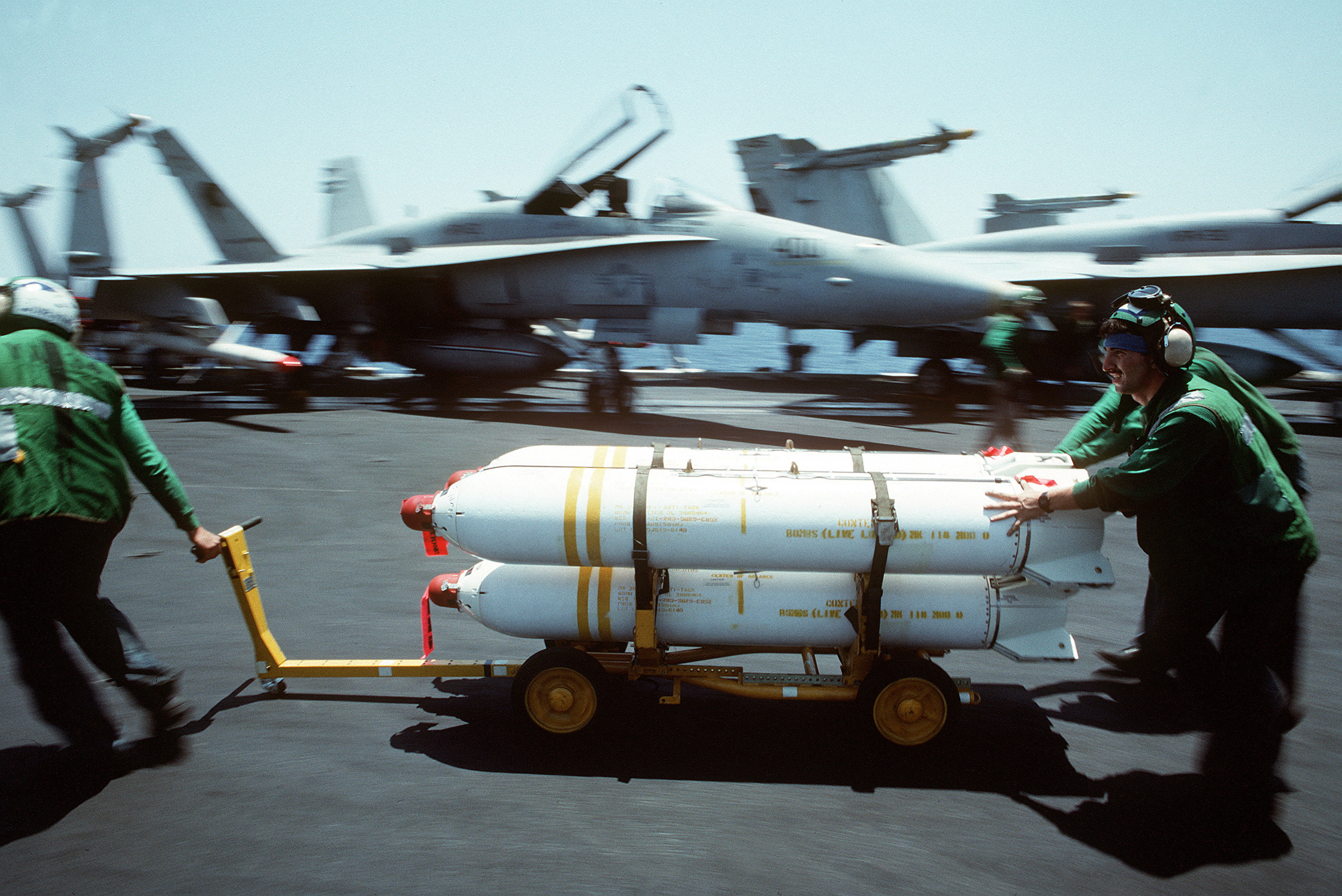 U.S. Navy maintenance crewmen move Mark 20 Rockeye II cluster bombs aboard an aircraft carrier in 1990
