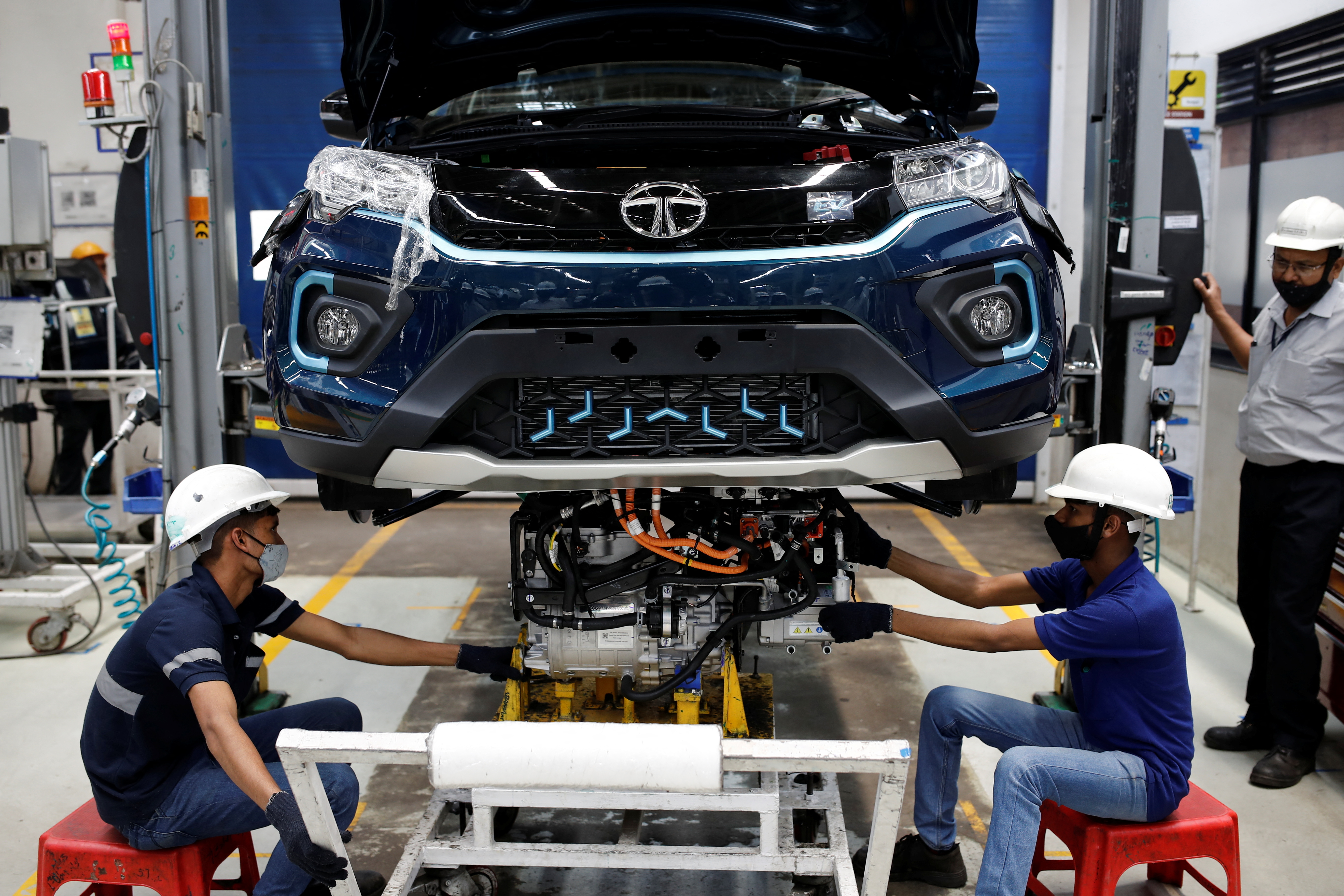 Workers install the electric motor inside a Tata Nexon electric sport utility vehicle (SUV) at the Tata Motors plant in Pune