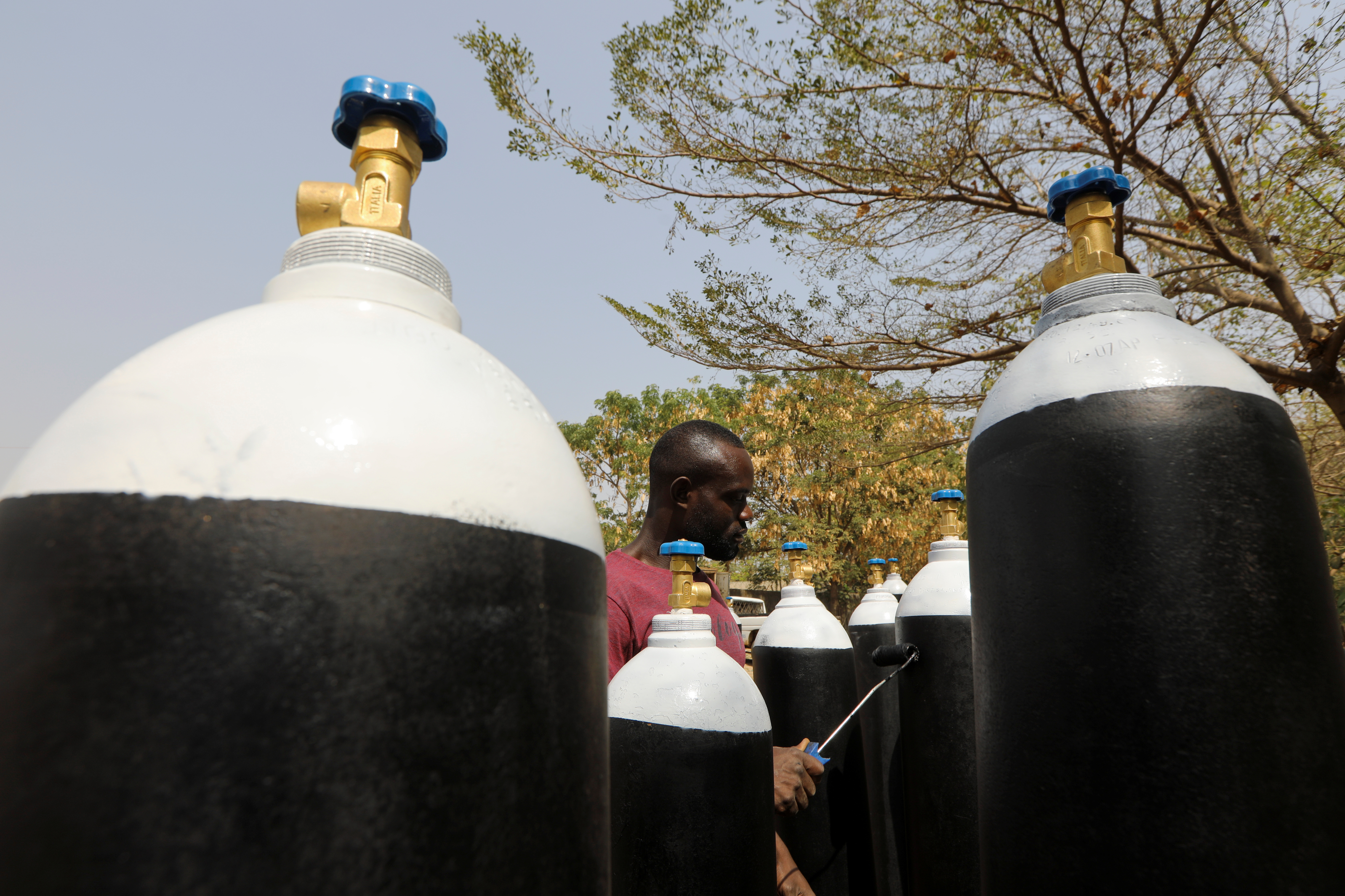 Man paints bottles used for storing oxygen in Abuja