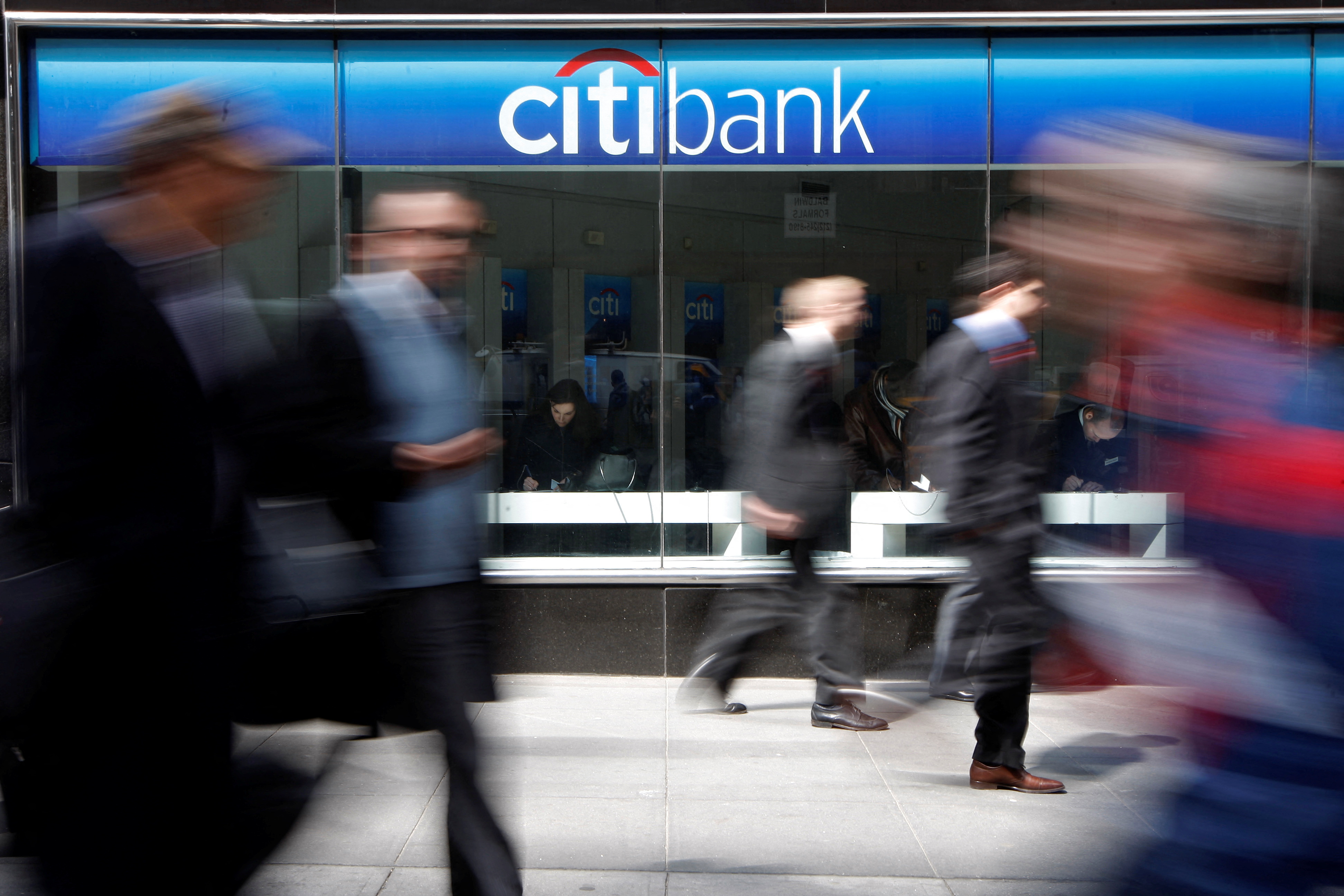 People walk past a CitiBank branch on Avenue of the Americas, in New York