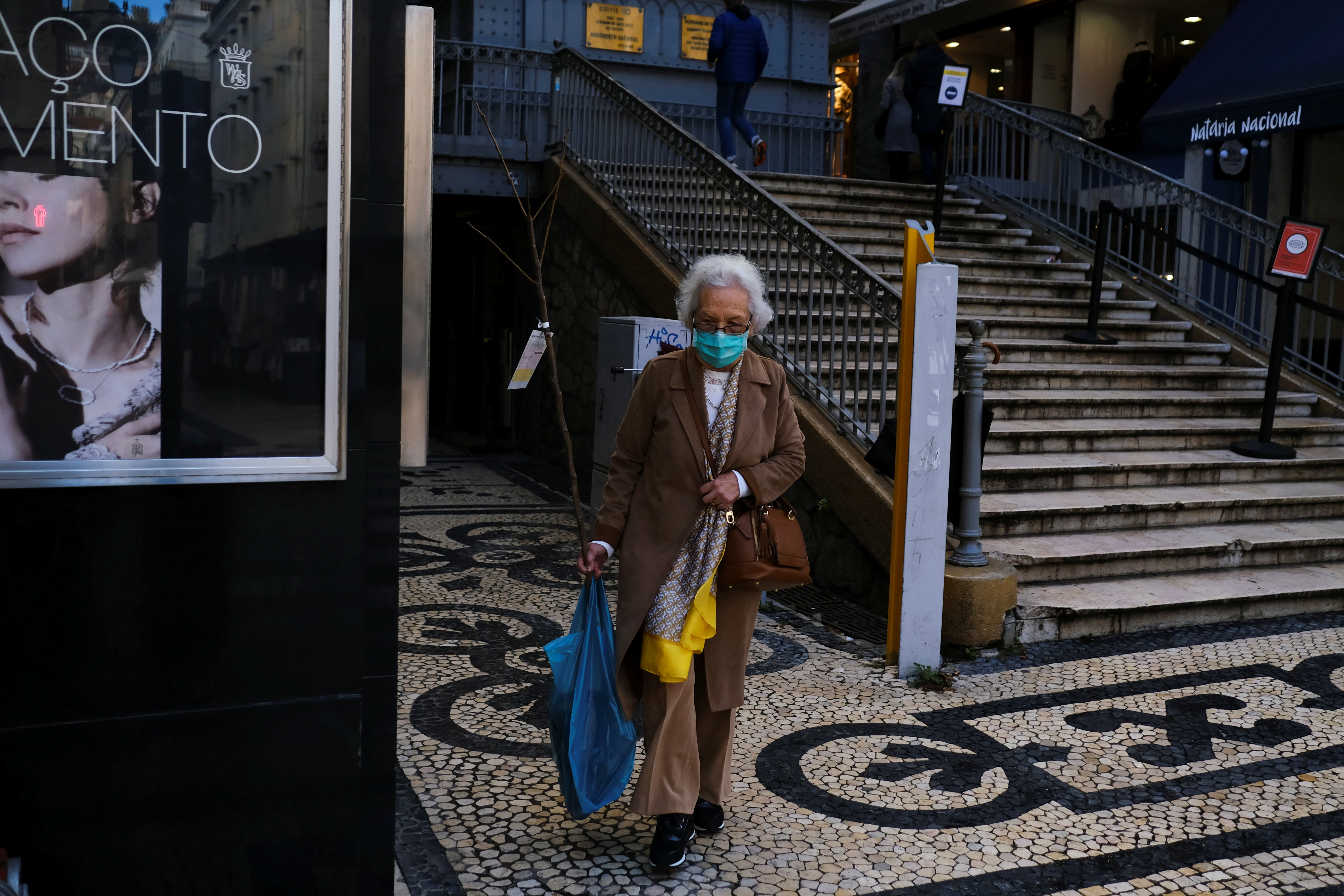 A woman wearing a protective mask due to coronavirus disease (COVID-19) pandemic walks in central Lisbon, Portugal, November 25, 2021. REUTERS/Pedro Nunes