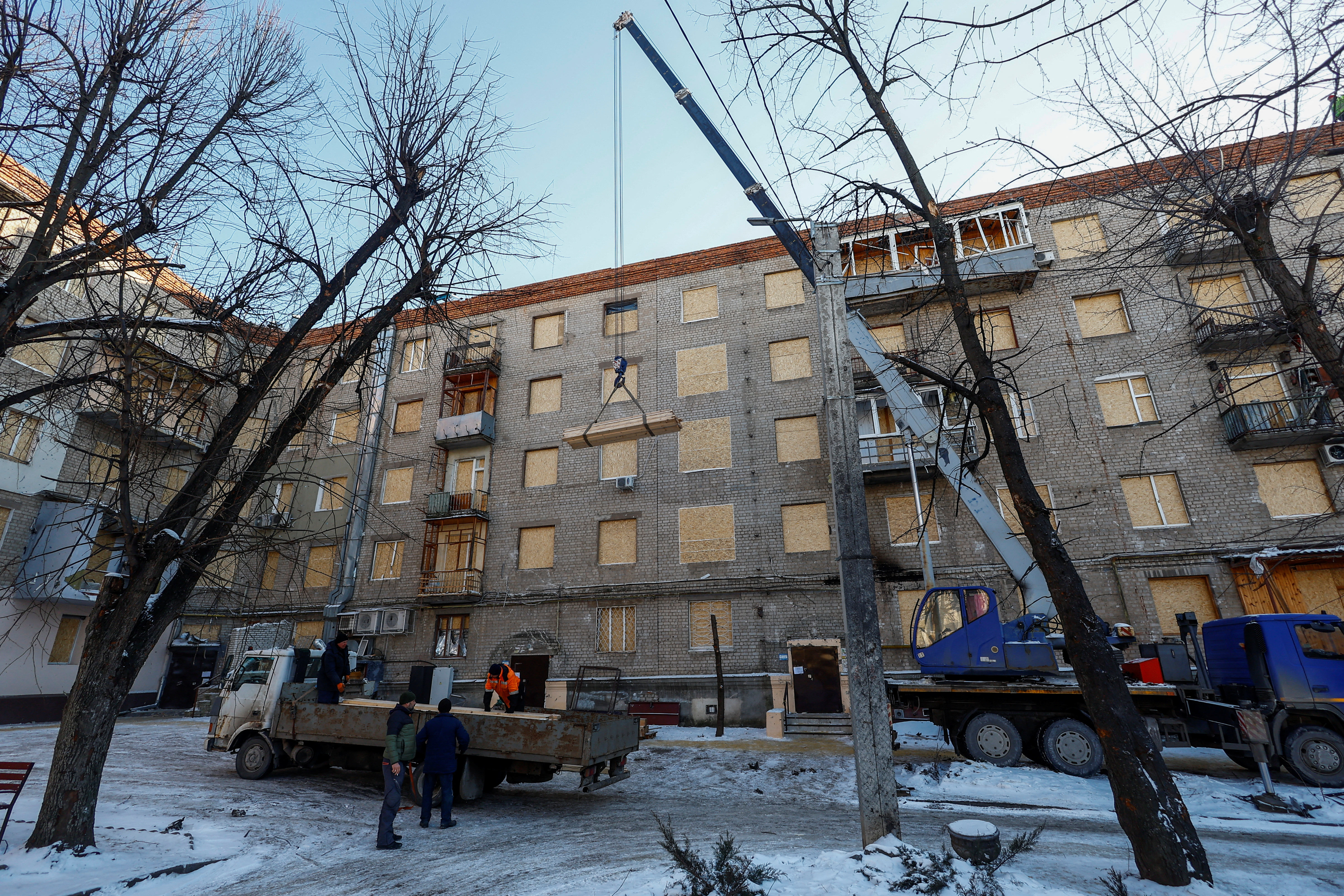 Workers repair an apartment building damaged during one of the Russian missile strikes in Kharkiv