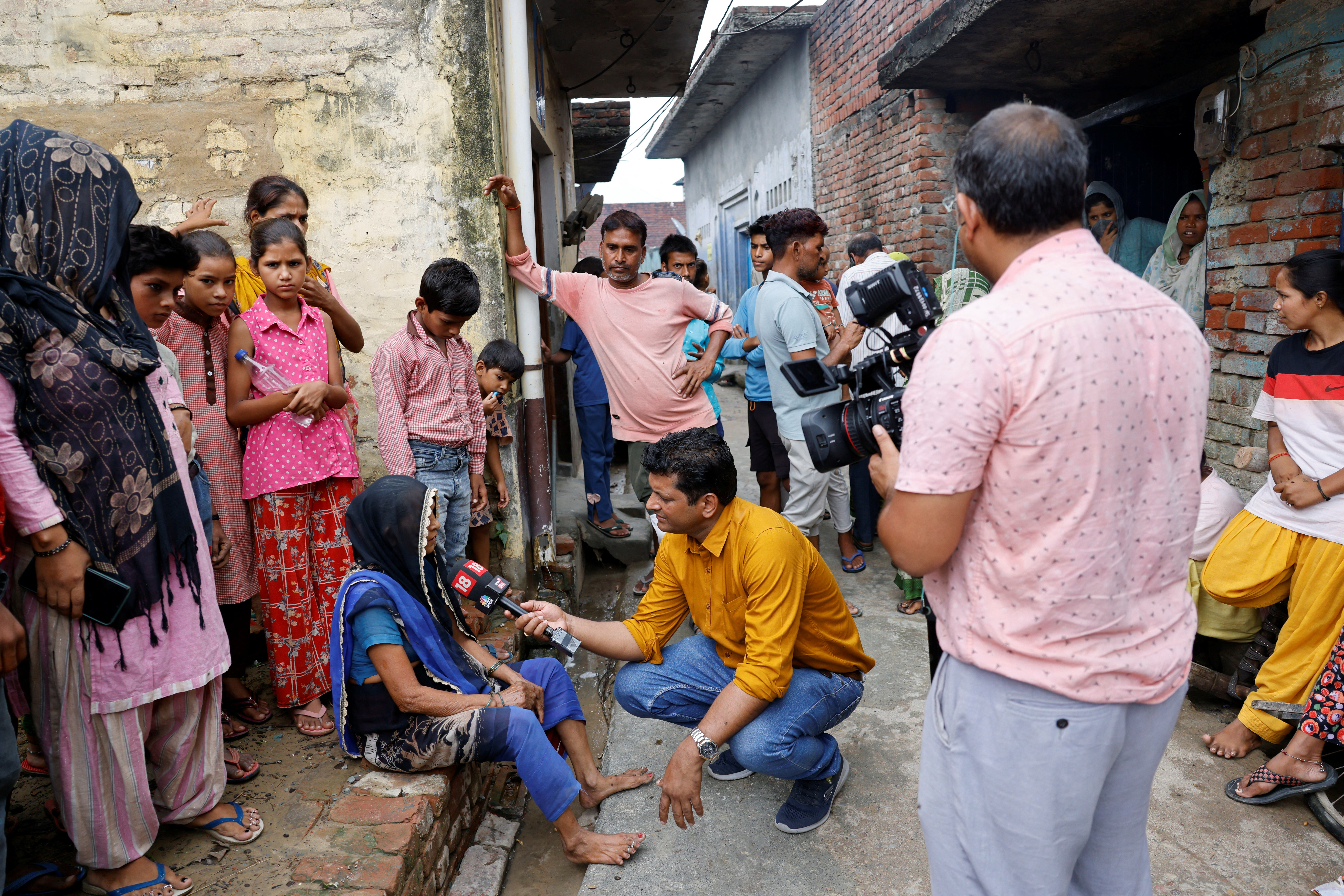 A news reporter interviews people in the village where Suraj Pal, also known as 'Bhole Baba', grew up, in Bahadurnagar in the northern state of Uttar Pradesh