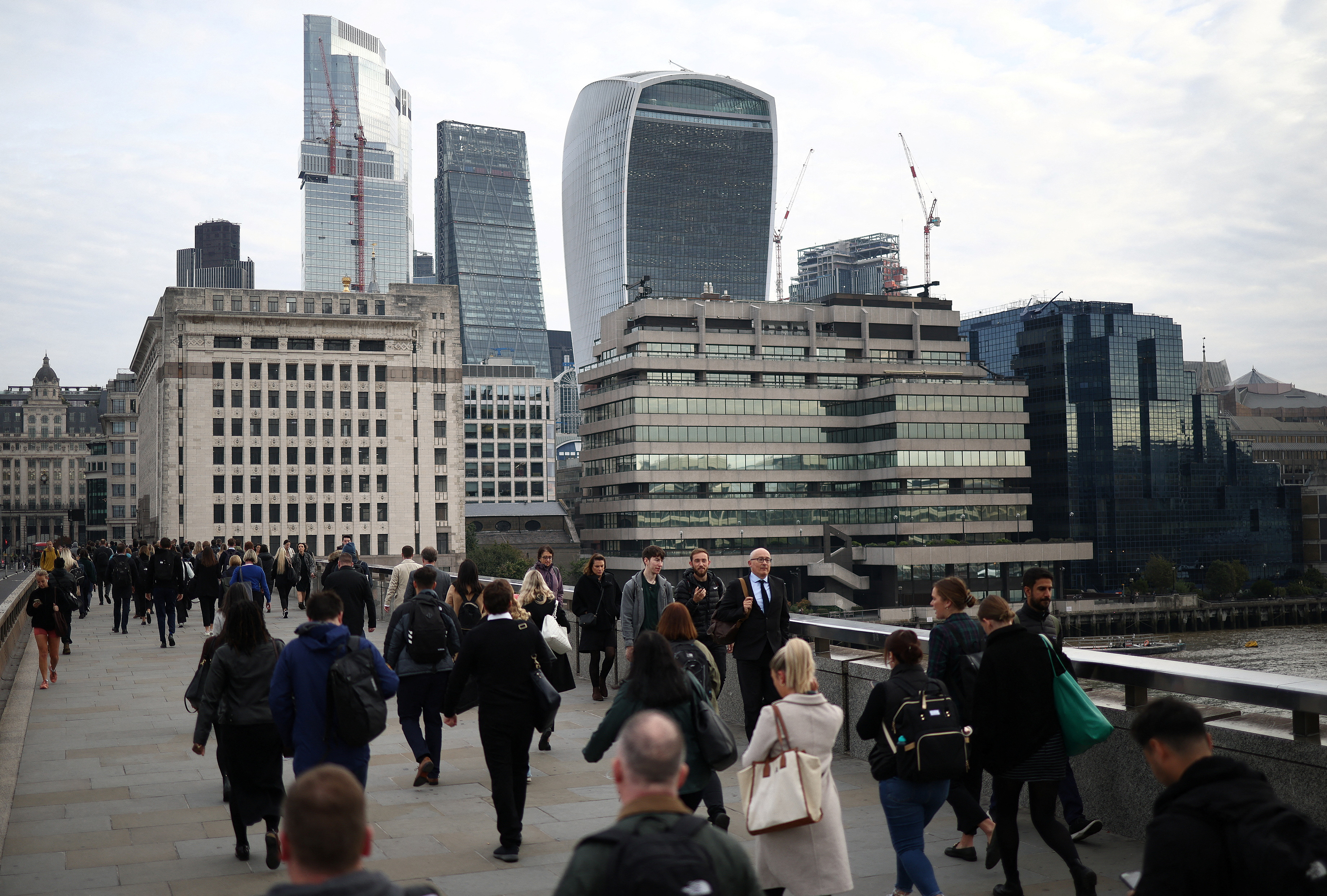 People walk over London Bridge towards the City of London financial district during rush hour in London