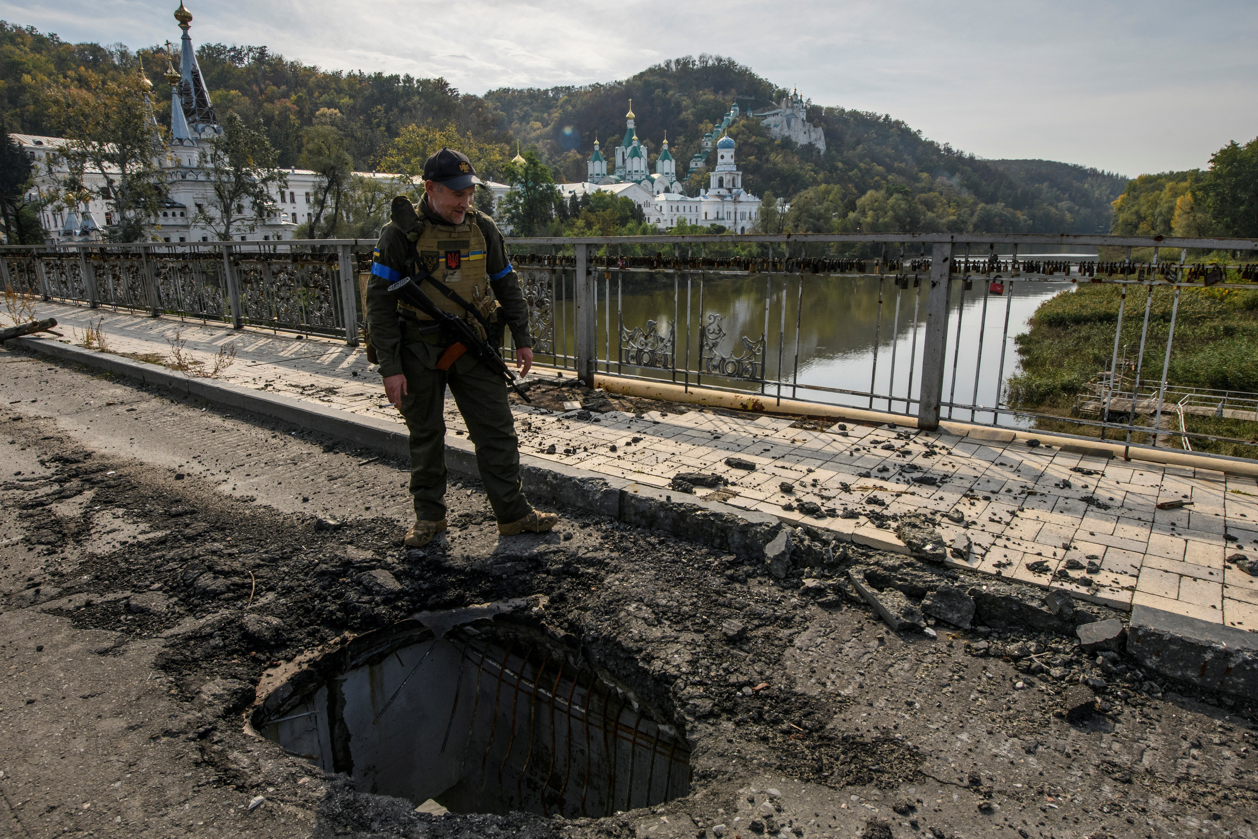 Service member of Ukraine's National Guard stands at a destroyed bridge over the Siverskyi Donets river in the town of Sviatohirsk