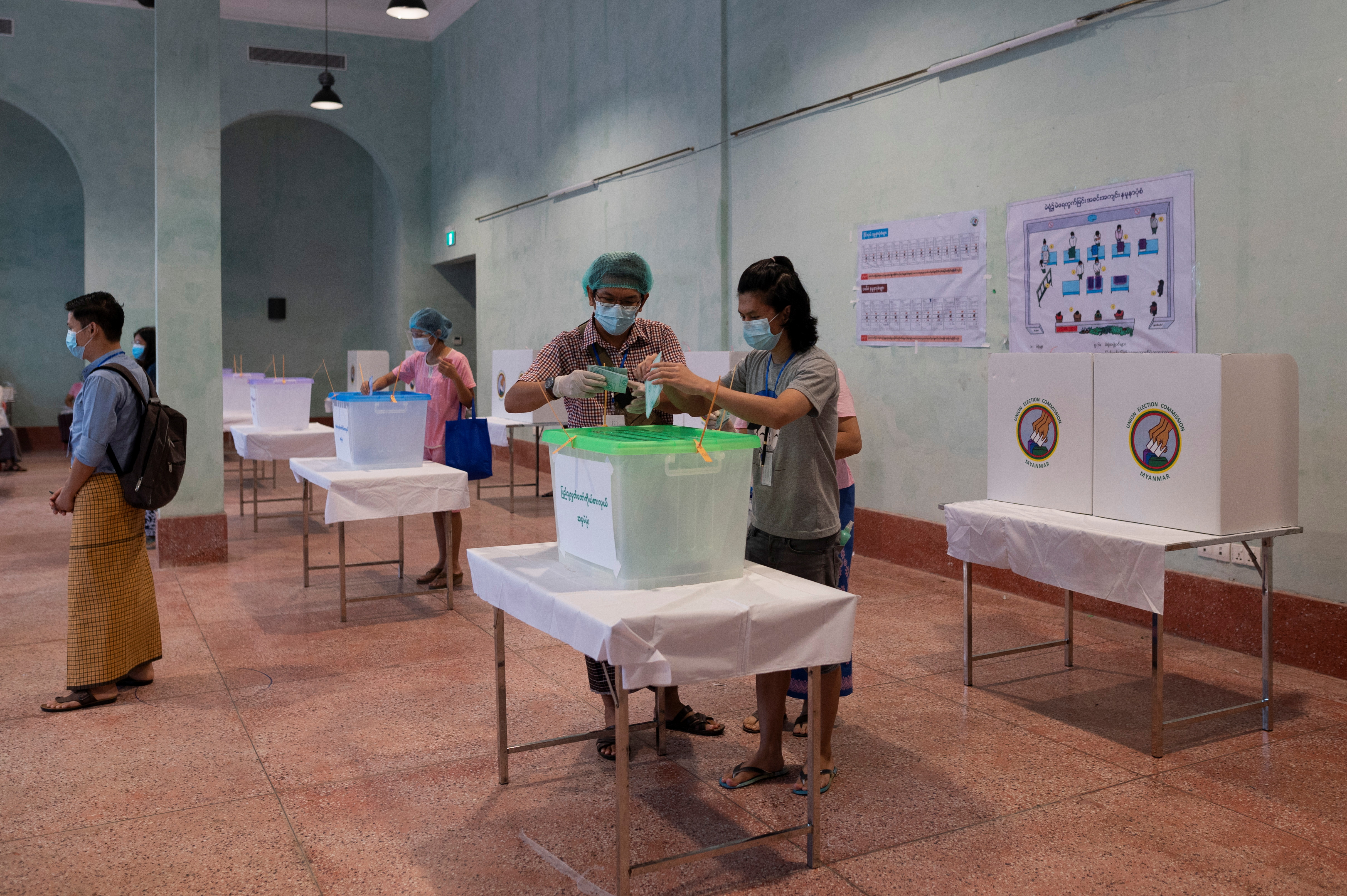 A woman wearing a protective face masks casts her ballot for the general election at a polling station in Yangon