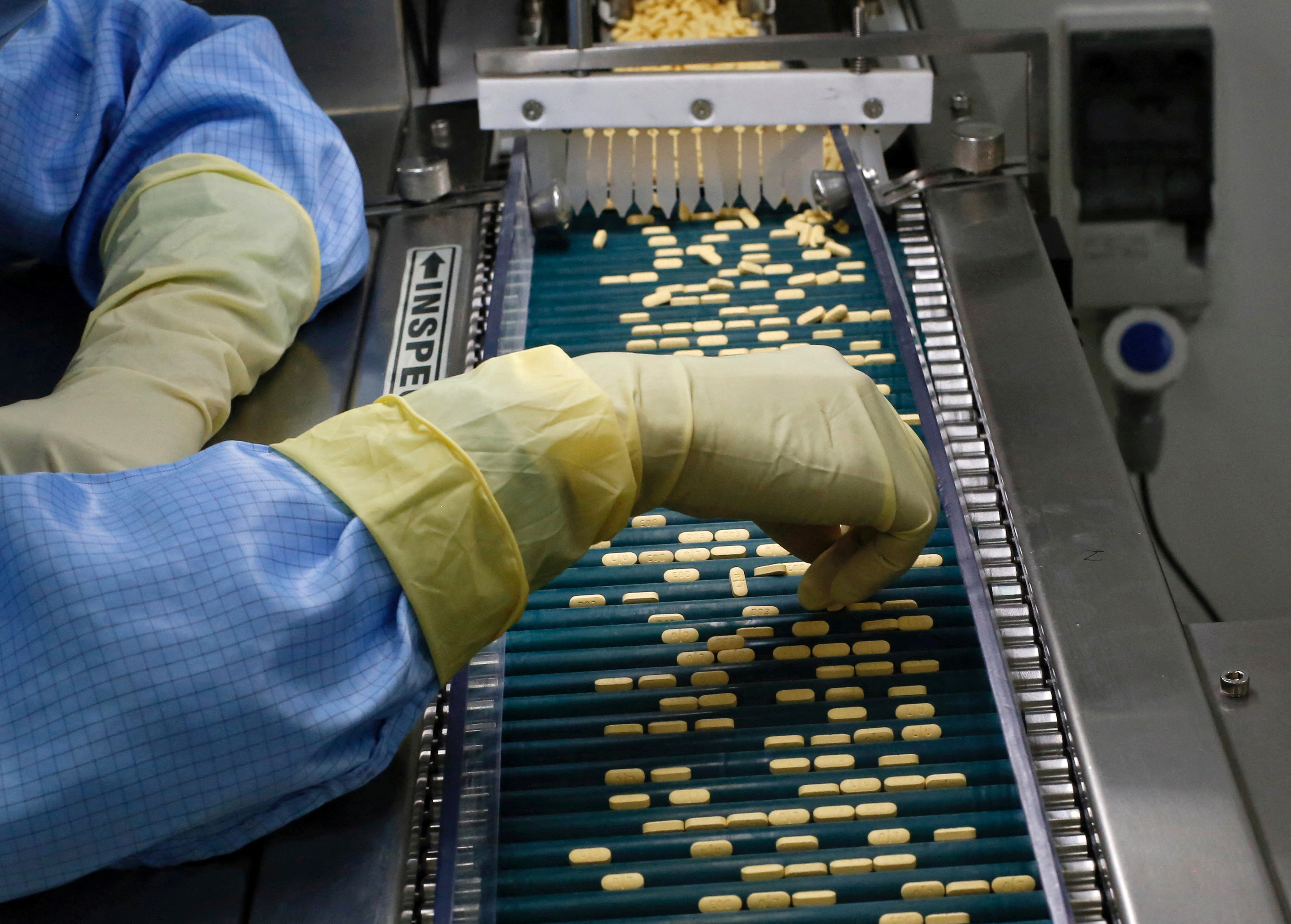 An employee inspects tablets as they move along the production line at a pharmaceutical plant of Lupin, India's No. 2 drugmaker, in Verna