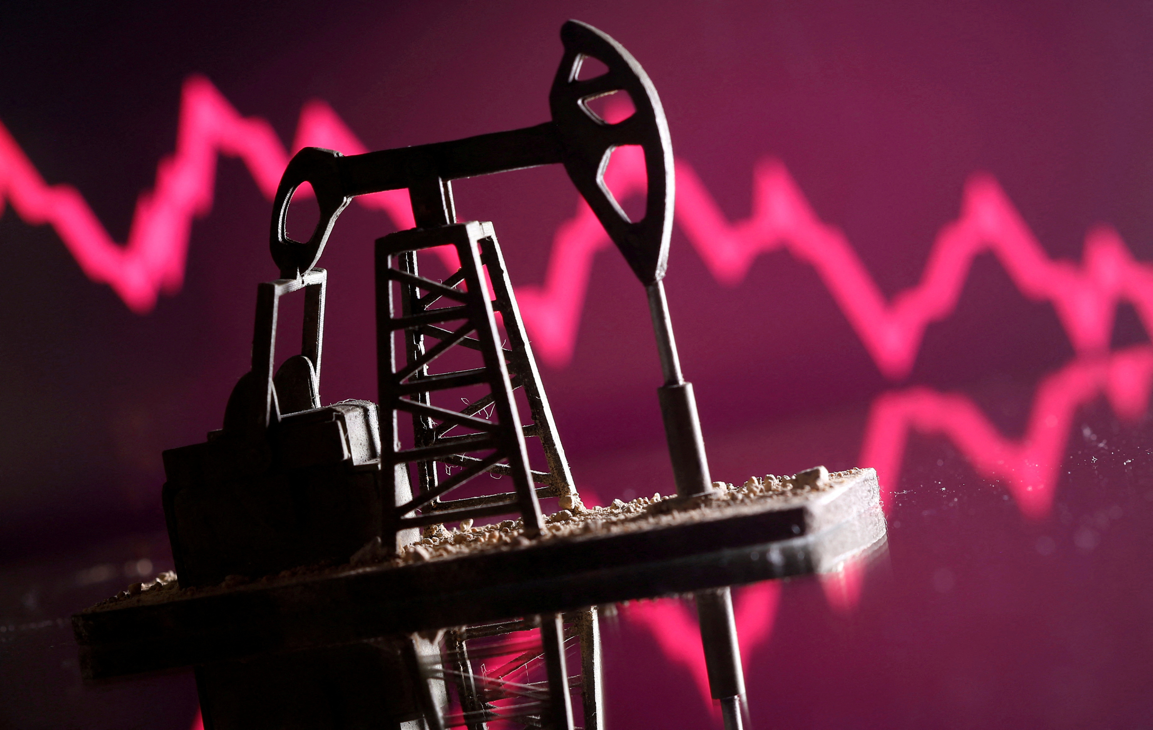 A 3D printed oil pump jack is seen in front of displayed stock graph in this illustration picture