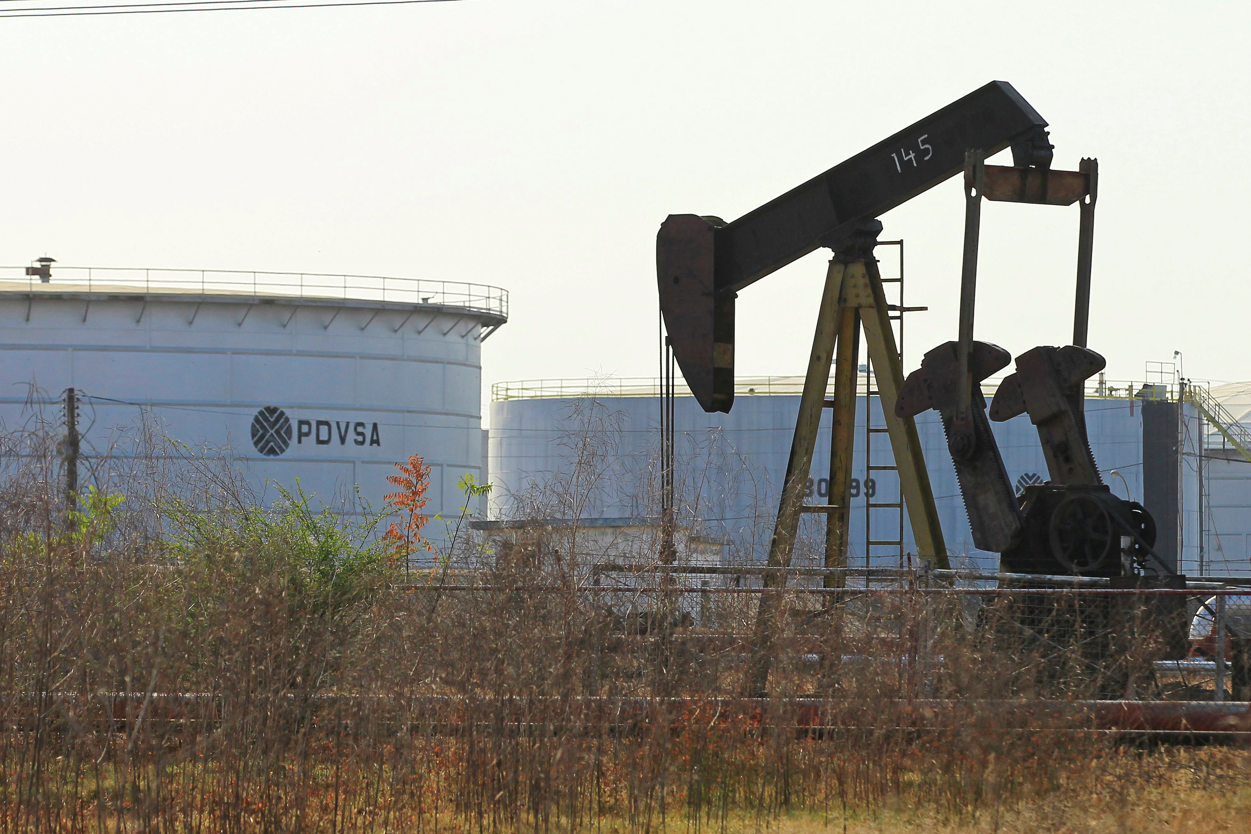 An oil pumpjack and a tank with the corporate logo of state oil company PDVSA are seen in an oil facility in Lagunillas