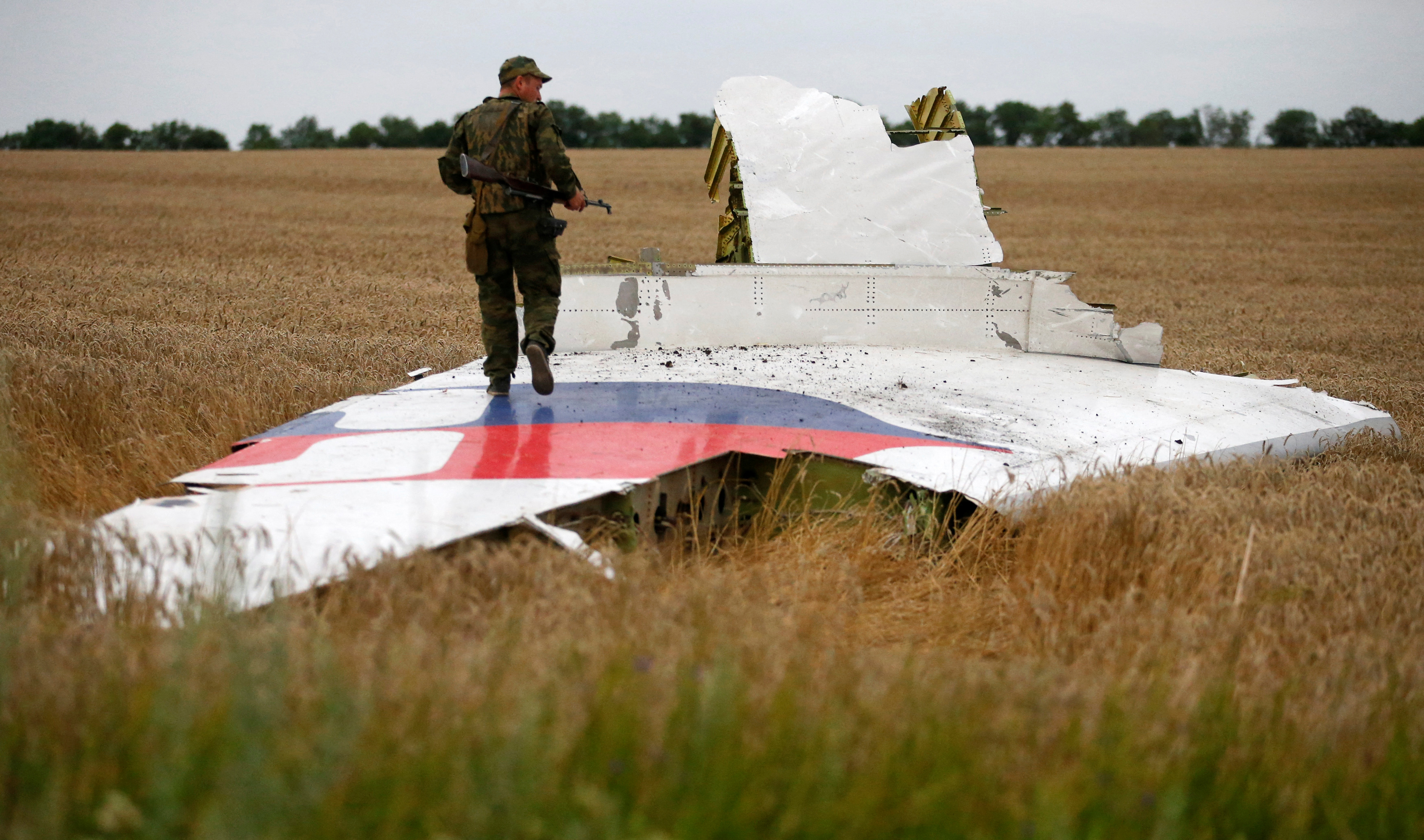 An armed pro-Russian separatist stands on part of the wreckage of the Malaysia Airlines Boeing 777 plane after it crashed near the settlement of Grabovo in the Donetsk region