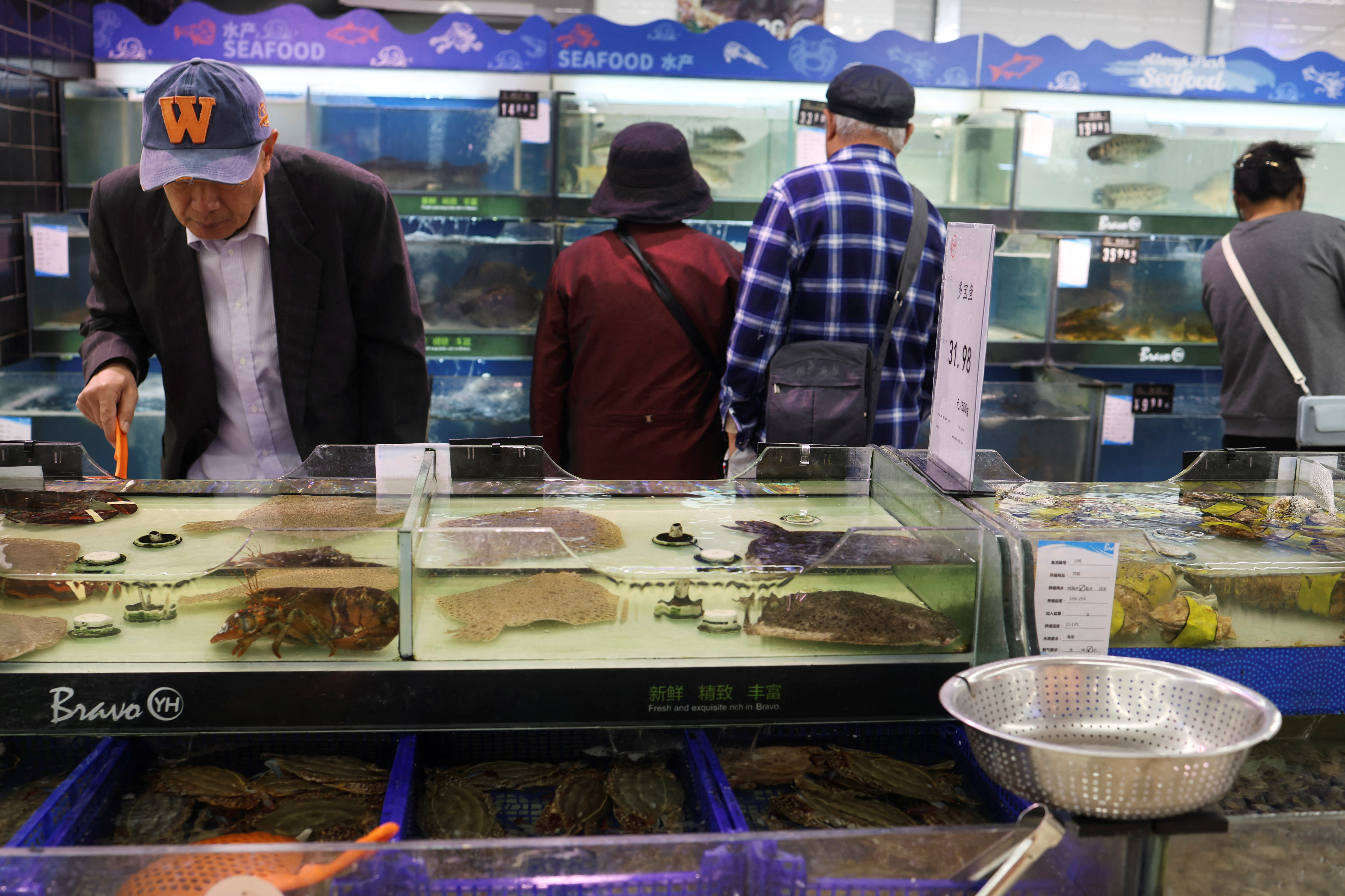 Customers look at live seafood displayed at a supermarket in Beijing