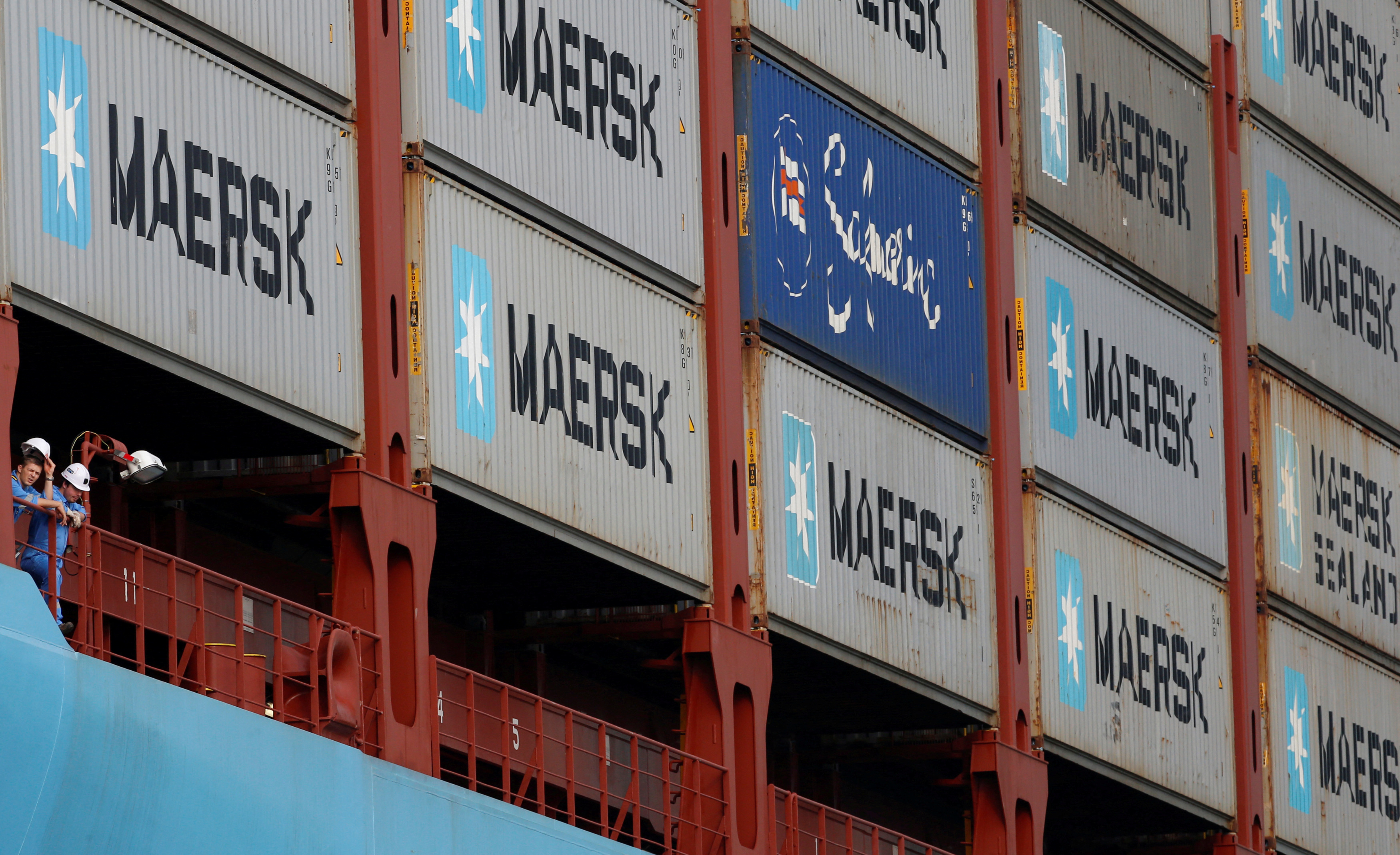 Crew members look out from the MV Maersk Mc-Kinney Moller, as it berths during its maiden port of call at a PSA International port terminal in Singapore